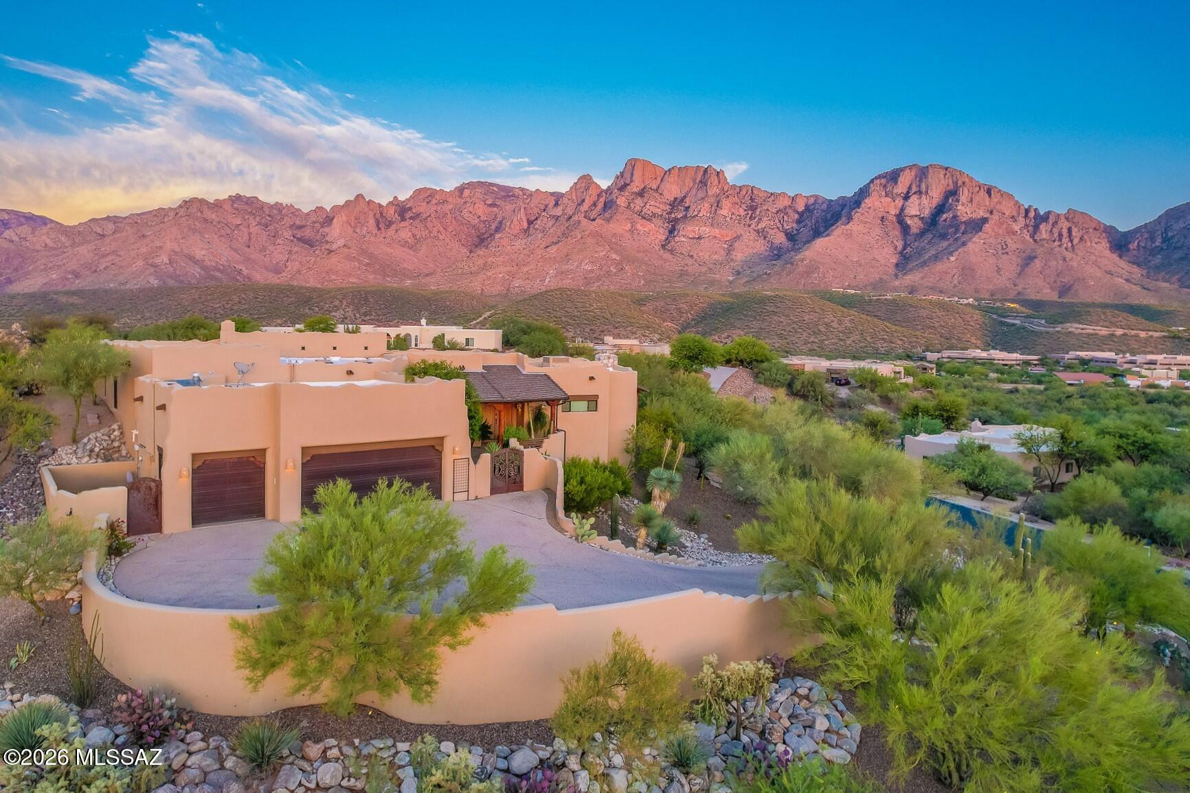 Experience authentic Santa Fe luxury in this custom-built masterpiece on one of the premier view lots in prestigious gated Palisades Point in Oro Valley. Perfectly positioned to capture breathtaking panoramic views of the Pusch Ridge Wilderness, enjoy dramatic granite-faced cliffs, towering saguaros, unforgettable sunsets, and abundant natural beauty from nearly every room. Rich architectural details include soaring saguaro rib ceilings, authentic viga beams, hand-crafted finishes, and timeless Southwestern character. The beautifully updated contemporary kitchen blends modern style with classic Santa Fe design, creating an ideal space for entertaining. A rare opportunity to own an exceptional desert retreat in one of Oro Valley's most sought-after communities.