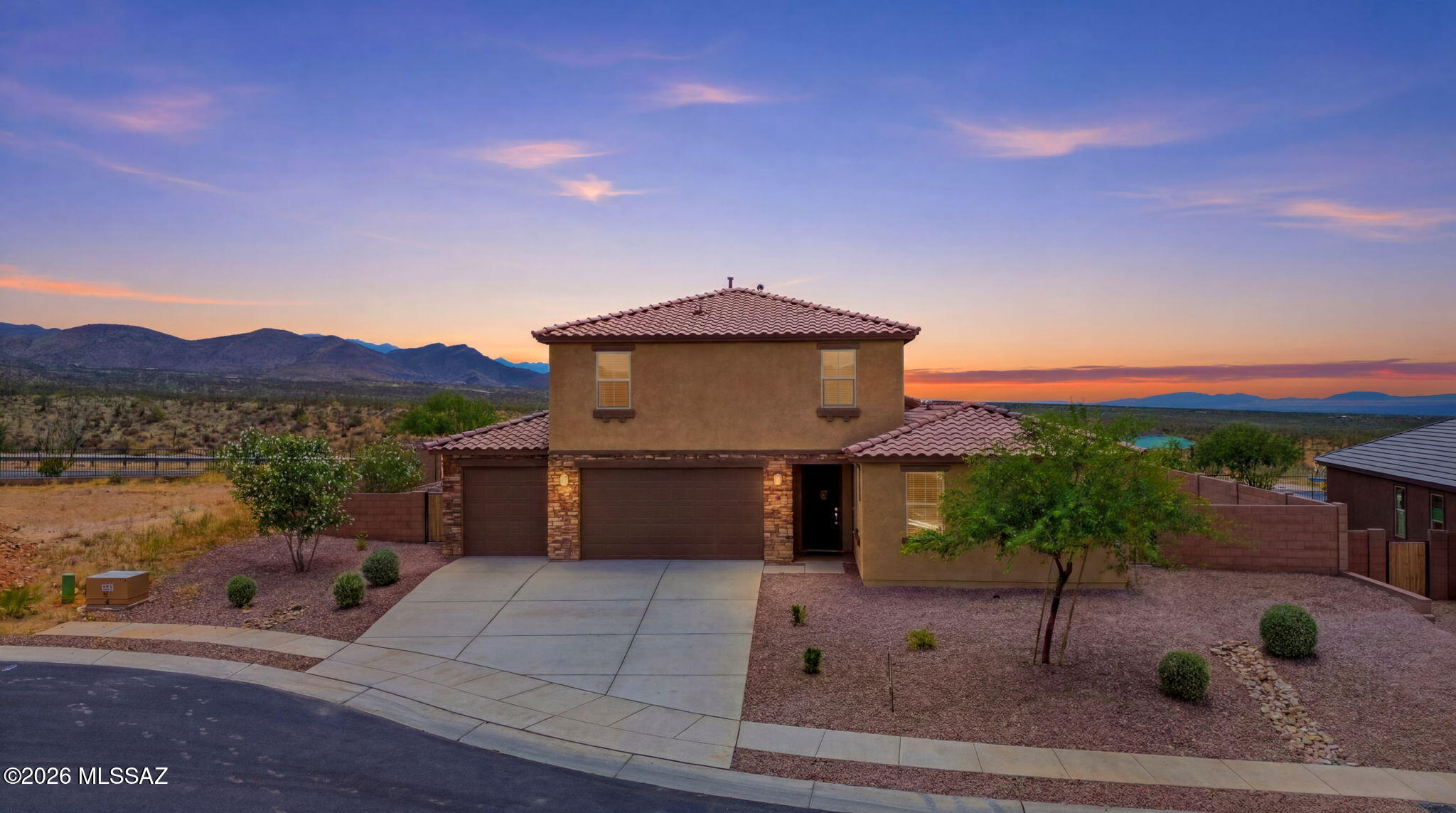 Experience the pinnacle of multigenerational living in this spectacular 2023-built former model home, boasting 2,749 square feet of thoughtfully designed luxury. Positioned perfectly to capture world-class Southern Arizona sunsets with no rear neighbors, this 5-bedroom, 3.5-bathroom estate features Lennar's highly coveted NextGen® attached guest suite. The private suite functions as its own home, complete with a dedicated entrance, kitchenette, bedroom, full bathroom, and independent laundry room--perfect for dual-living, long-term guests, or a premium home office.The main home welcomes you with an meticulously designed chef's kitchen, featuring sleek stainless steel appliances, premium granite countertops, and classy custom cabinetry. A large breakfast bar island offers an ideal gatherin space with ample integrated storage. Beautiful ceramic tile flows through the main living areas, while plush, cozy carpeting warms the bedrooms. Every bathroom is elegantly finished with modern fixtures. Step outside into your private desert oasis. The premium backyard is fully finished with modern pavers, pristine artificial turf, decorative gravel, and mature trees. The backyard patio area provides the perfect setting for sipping your beverage of choice while watching the desert skies change colors. Complete with a rare and massive 4-car garage for vehicles and desert toys, this turnkey model home offers an unmatched Southern Arizona lifestyle. All staged items will be removed before COE.
