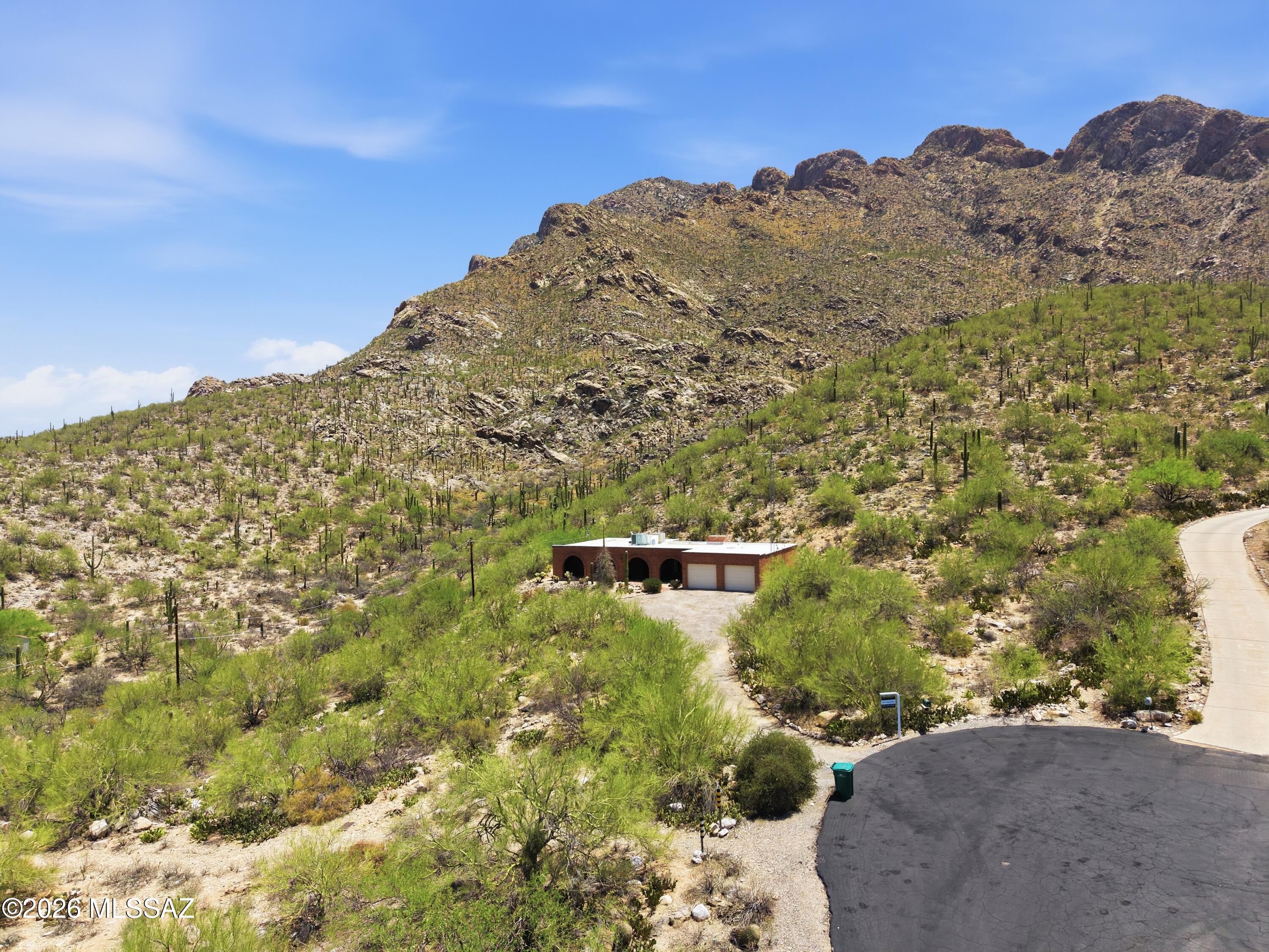 Tucked against the rugged foothills of Pusch Ridge in Oro Valley, this solid brick home delivers a rare combination of dramatic mountain views and true Sonoran Desert privacy. Arched brick doorways anchor a spacious living area anchored by a wood-burning fireplace, with sliding glass doors that frame breathtaking ridge views from nearly every room. The layout includes three bedrooms, a primary suite with dual vanities and walk-in shower, a second full bath, and a 2-car garage. A covered rear patio overlooks a walled native courtyard filled with saguaro, barrel cactus, and ocotillo -- all backing directly to the mountain. A canvas ready for your vision.