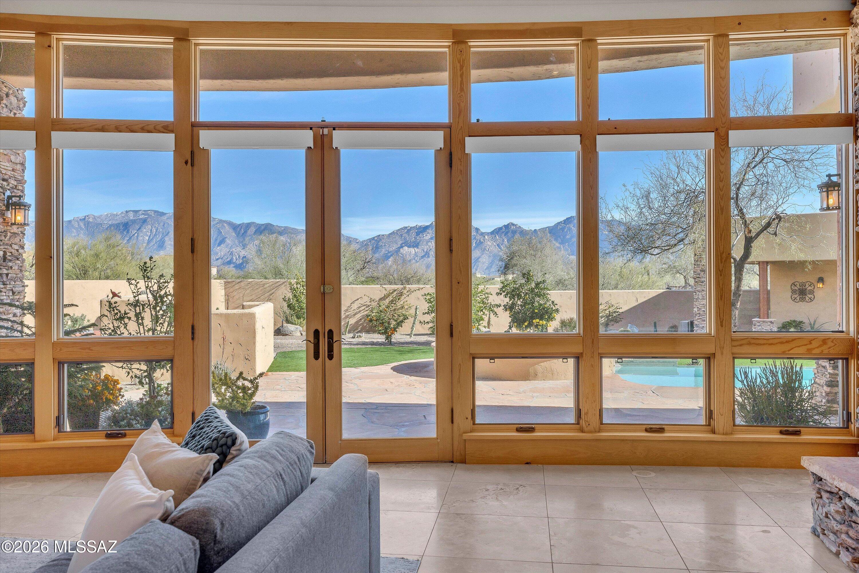 A rare opportunity within the guard-gated Stone Canyon golf community, this custom Oro Valley residence commands sweeping Catalina Mountain views with ever-changing light from sunrise through sunset. The great room sets an elegant tone with soaring ceilings, a dramatic stacked stone fireplace, and a curved wall of floor-to-ceiling windows opening to the pool and Catalinas. Mountain views extend into the dining area and kitchen, creating a seamless connection to the natural setting. The kitchen is well-appointed with white cabinetry, a navy island, quartz countertops, professional appliances, and gas cooking in an open layout designed for easy living and entertaining. The primary suite offers French door patio access, a corner kiva fireplace, and its own postcard perfect mountain view. The spa-inspired primary bath features dual granite vanities, a deep curved soaking tub, and a glass-enclosed shower with glass block detail that fills the space with natural light. Guest bedrooms each feature ensuite baths. A see-through fireplace connects the great room and dining room -- an architectural detail that anchors both spaces with warmth and character. The dining room opens independently to the pool terrace through French doors, with citrus trees and desert plantings framing the outdoor experience. A fully separate 548 sq ft guest house adds exceptional flexibility for extended family or guests. Outside, the heated pool, spa, built-in BBQ, and covered patios are perfectly oriented to the Catalinas -- all set on nearly two acres within one of Oro Valley's most sought-after guard-gated communities, offering golf, tennis, pickleball, and resort-style amenities. A home of this setting and scale, priced to invite you to make it entirely your own.