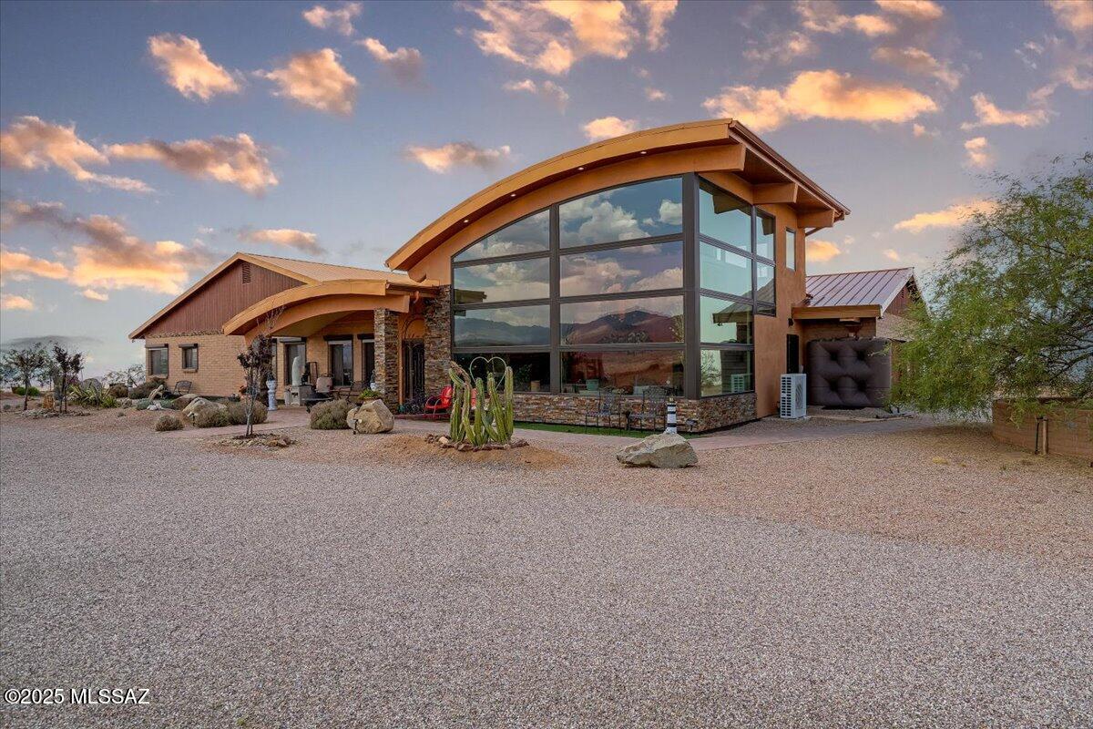 Discover elevated desert living at its finest in this custom 3,596 sq ft estate perched on 5.28 acres at one of Oracle's highest vantage points. Surrounded by extraordinary 360° mountain views and of multiple ranges, with a commanding perch that overlooks the entire town of Oracle.  This meticulously upgraded residence delivers rare privacy, refined finishes, and a layout designed for comfort, security, and versatility. 
The home features 4 bedrooms, 3 baths, and a flexible bonus space which could ideal for an office, fitness area, media space, or creative studio. the impressive 896 sq ft guest addition expands the living experience with floor-to-ceiling glass that frames sweeping natural scenery--perfect for visitors and multi-generational living at its best! The interior has been fully renovated with high-quality materials, updated cabinetry, upgraded counters, and modern flooring. Expansive windows bring in abundant daylight while capturing panoramic views from nearly every angle. A bright sunroom enhances the home year-round, naturally warming the living areas during cooler months and offering a comfortable space to enjoy the changing seasons.

Designed with security and longevity in mind, the property includes rolling window shutters, reinforced exterior doors, a standing seam metal roof, and a leaf-filter gutter system. These features create a worry-free lock-and-leave environment with exceptional durability.

Outside, a chip-seal driveway leads to your 8 garages one attached and two detached plus an attached greenhouse. The land offers mature fruit trees, wide-open space suitable for horses, and room for additional amenities, including an area usable as a helipad. A rainwater harvesting system with multiple collection barrels contributes to sustainable living and reduces reliance on municipal water.

This horse property combines elevated luxury, practical upgrades, and a setting that must be seen to be believed. From sunrise to sunset, every moment here is framed by unmatched scenery and peaceful desert beauty. This is a rare opportunity to own a true hilltop estate offering privacy, elevation and some of the most expansive views in the area,