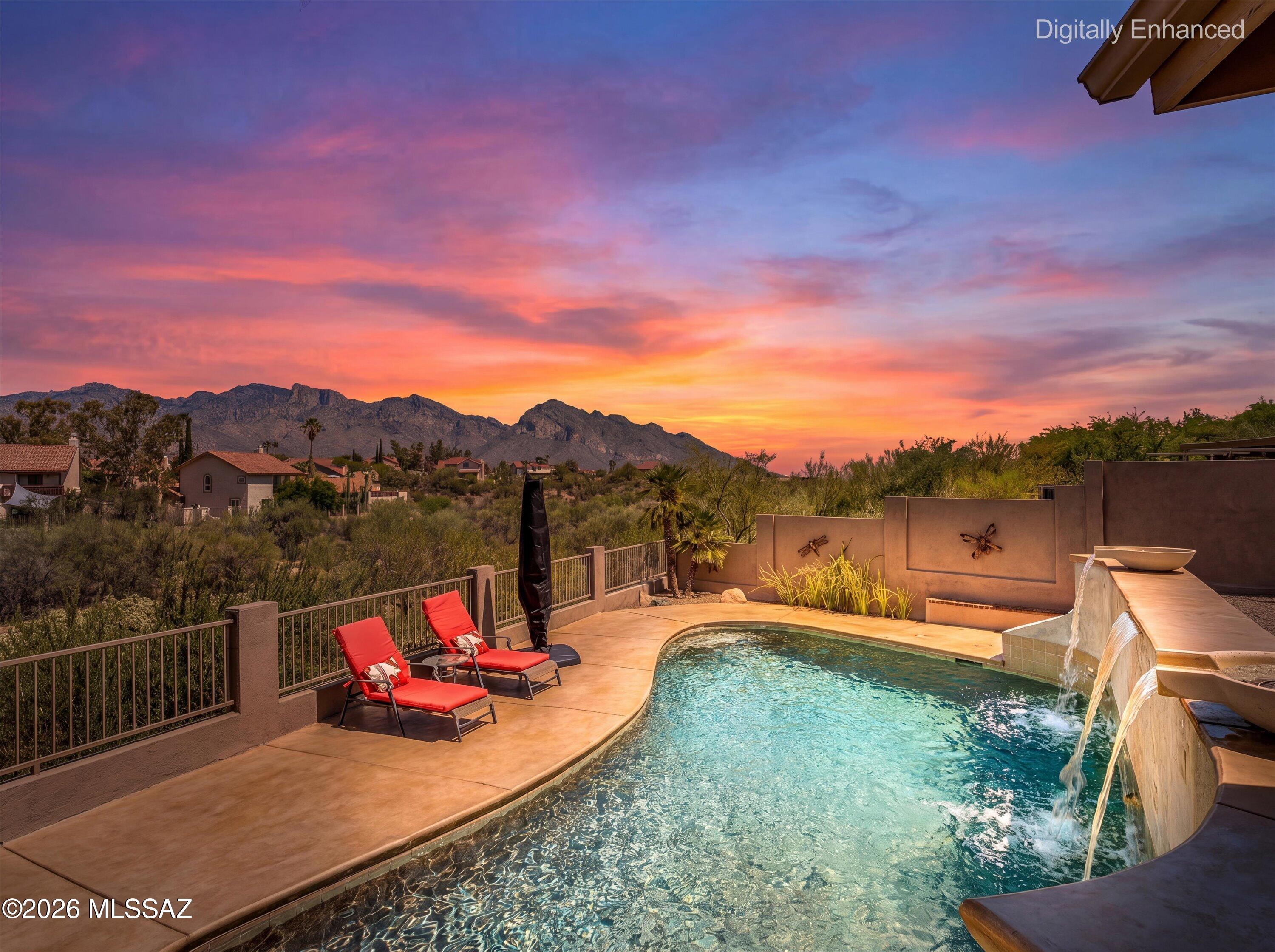 Commanding breathtaking mountain views, this exceptional 5-bedroom, 3-bath residence offers 2,460 sq. ft. of refined living in the heart of Oro Valley. Thoughtfully upgraded throughout, the home seamlessly blends elegance, comfort, and Arizona's coveted indoor-outdoor lifestyle.

The resort-inspired backyard is designed for both relaxation and entertaining, featuring a gas fire pit, outdoor hot-water shower, ambient landscape lighting, mature fig and Valencia orange trees, and private access to the community walking path. Pool equipment is prepared for solar heating, and electrical service is in place for a future spa.

Inside, a beautifully remodeled kitchen showcases a GE wall oven, induction cooktop, wine refrigerator, and sophisticated finishes. Custom details abound, including a handcrafted floating sycamore mantel, imported Turkish stacked stone fireplace, custom oak staircase with wrought-iron railing, and integrated speaker wiring throughout the main living areas and backyard.

Additional enhancements include Milgard Tuscany dual-pane windows, Andersen clad patio doors with stained wood interiors, a Therma-Tru fiberglass entry door, and a VIPEQ spray cork exterior coating for enhanced energy efficiency and year-round comfort.

A rare opportunity to own a meticulously upgraded Oro Valley home where luxury living meets spectacular mountain views