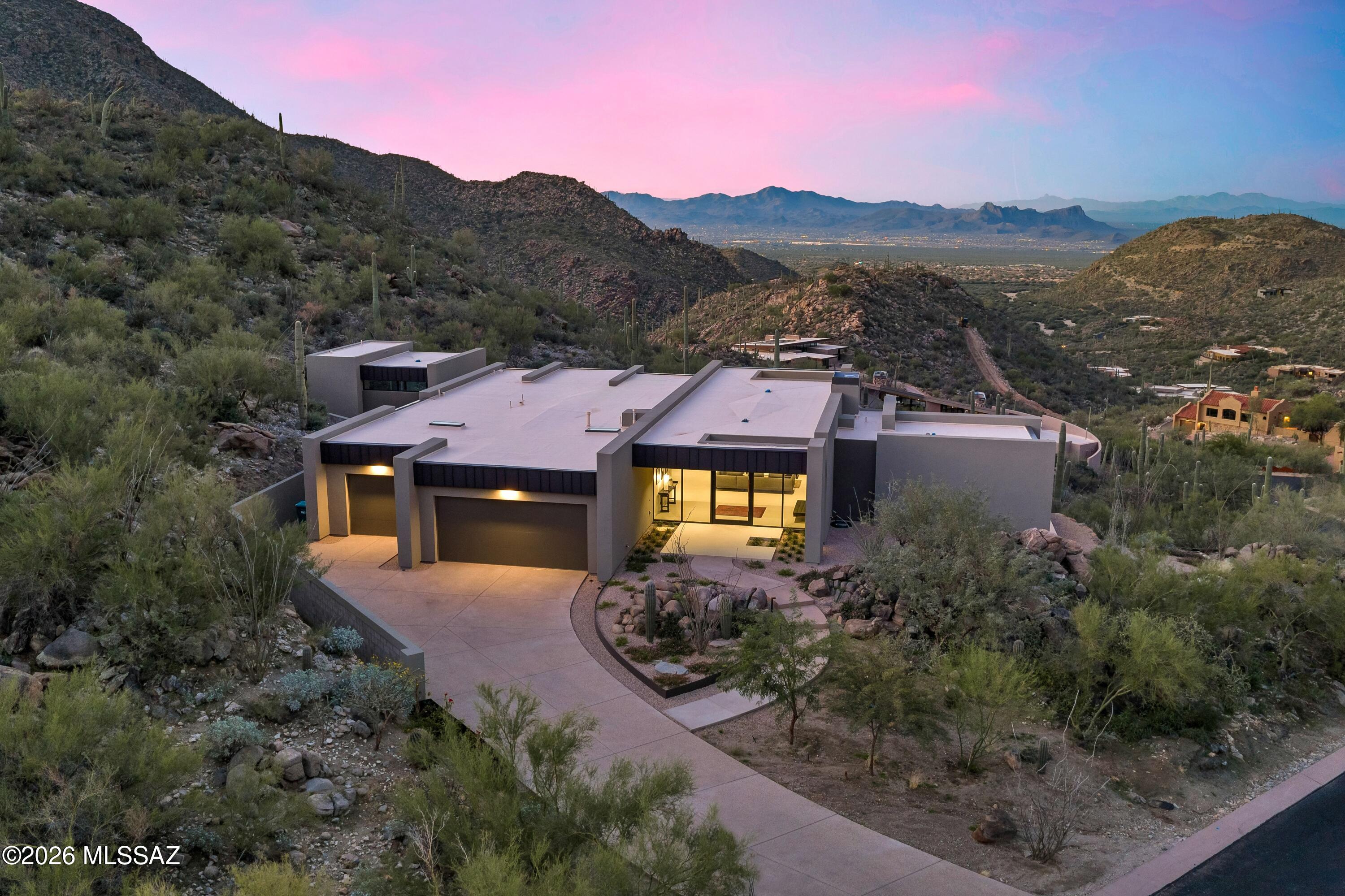 VIEWS FROM EVERY ROOM!! Completed in 2025, this brand-new residence was crafted from the ground up with thoughtful design and modern luxury at every turn. Perched on a premier hilltop homesite, the home was intentionally oriented to capture sweeping, unobstructed views from every room. Floor-to-ceiling windows wrap the entire residence, drawing the desert horizon, canyon walls, and ever-changing sky directly into the living spaces.
Designed by architect Serghei of SARI TERZI Designs, the home sits on a carefully selected lot within Dove Mountain's tranquil, gated Canyon Pass community--chosen specifically for its extraordinary vistas and natural serenity. The result is a rare blend of privacy, openness, and a seamless connection to the surrounding landscape. A striking rear façade of glass anchors the design, flooding the interior with natural light and framing the dramatic desert scenery. Expansive sliding glass doors open each room to its own private patio, creating effortless indoor-outdoor living and uninterrupted sightlines in every direction.  The property is presented as a three-bedroom home, featuring the primary suite and a versatile bedroom in the main house, complete with a generous full bath and closet. Inside, the home is elevated by custom, grain-matched walnut cabinetry by Summit Woodworking, thoughtfully integrated throughout the residence. The split floor plan places the primary suite on its own wing for maximum privacy, while the flexible bedroom sits opposite, ready to adapt to your lifestyle. For those dreaming of a pool, the generous lot offers ample space to design a custom outdoor oasis. The architect has even offered to create a personalized pool concept tailored to your vision and the home's breathtaking backdrop. This is a must-see -Call today for a showing!