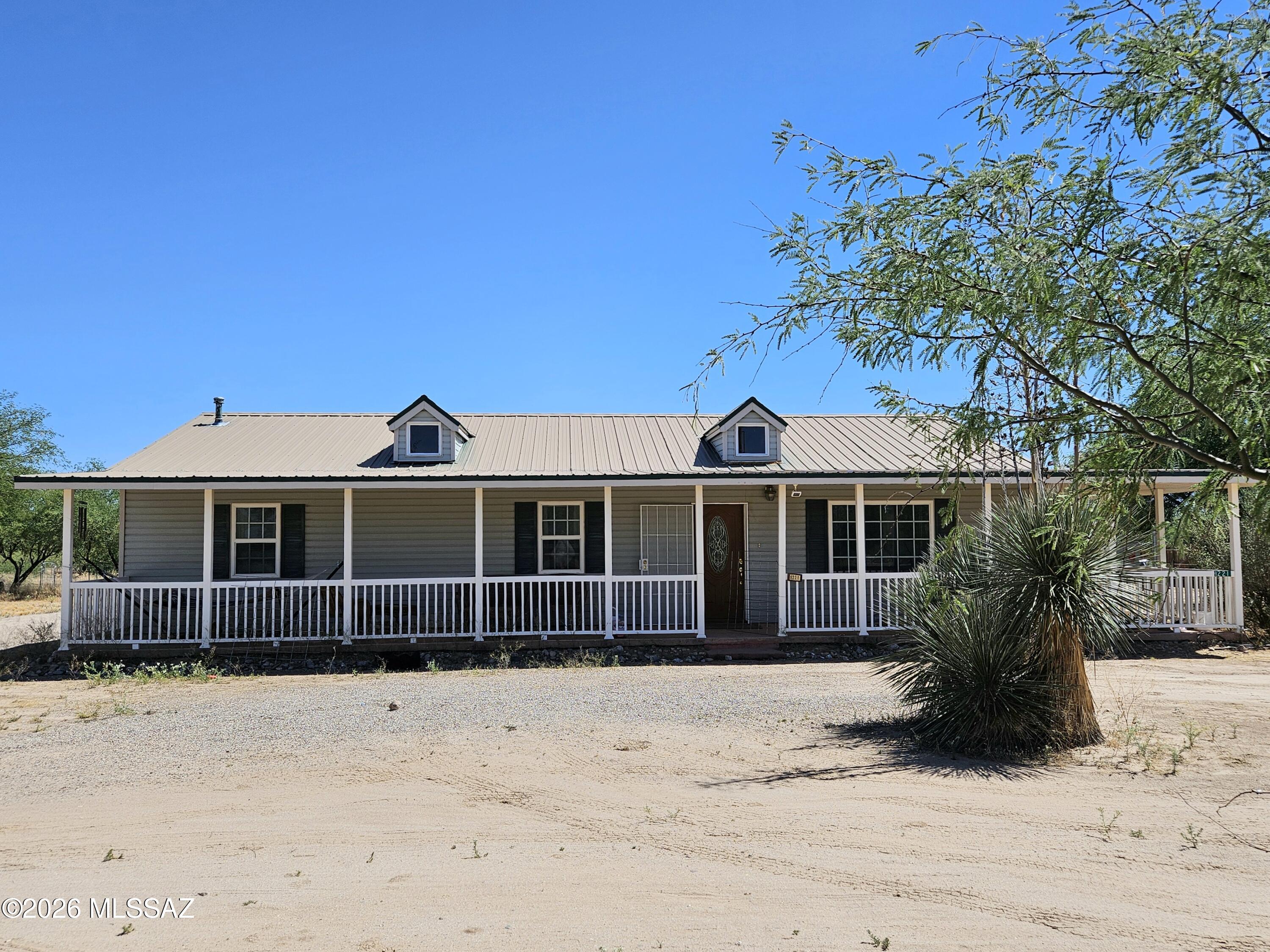 This well-maintained country home was built in 2006 and offers 1,500 sq. Ft. Of comfortable living space w/ 3 bed/2bath, a huge covered porch, mature shade trees & situated on 2 acres of flat/useable property that is partially fenced.  There is a 2,004 sq. Ft.  Steel Garage/equipment/storage building w/cement floors & has an upstairs apartment.  There is also a bungalow that has potential to be used as a guest house, art studio, hobby room or for additional enclosed storage.  Located in Pomerene w/quick access to I-10 for commuting. Come enjoy quiet, country living w/close proximity to shopping and restaurants.