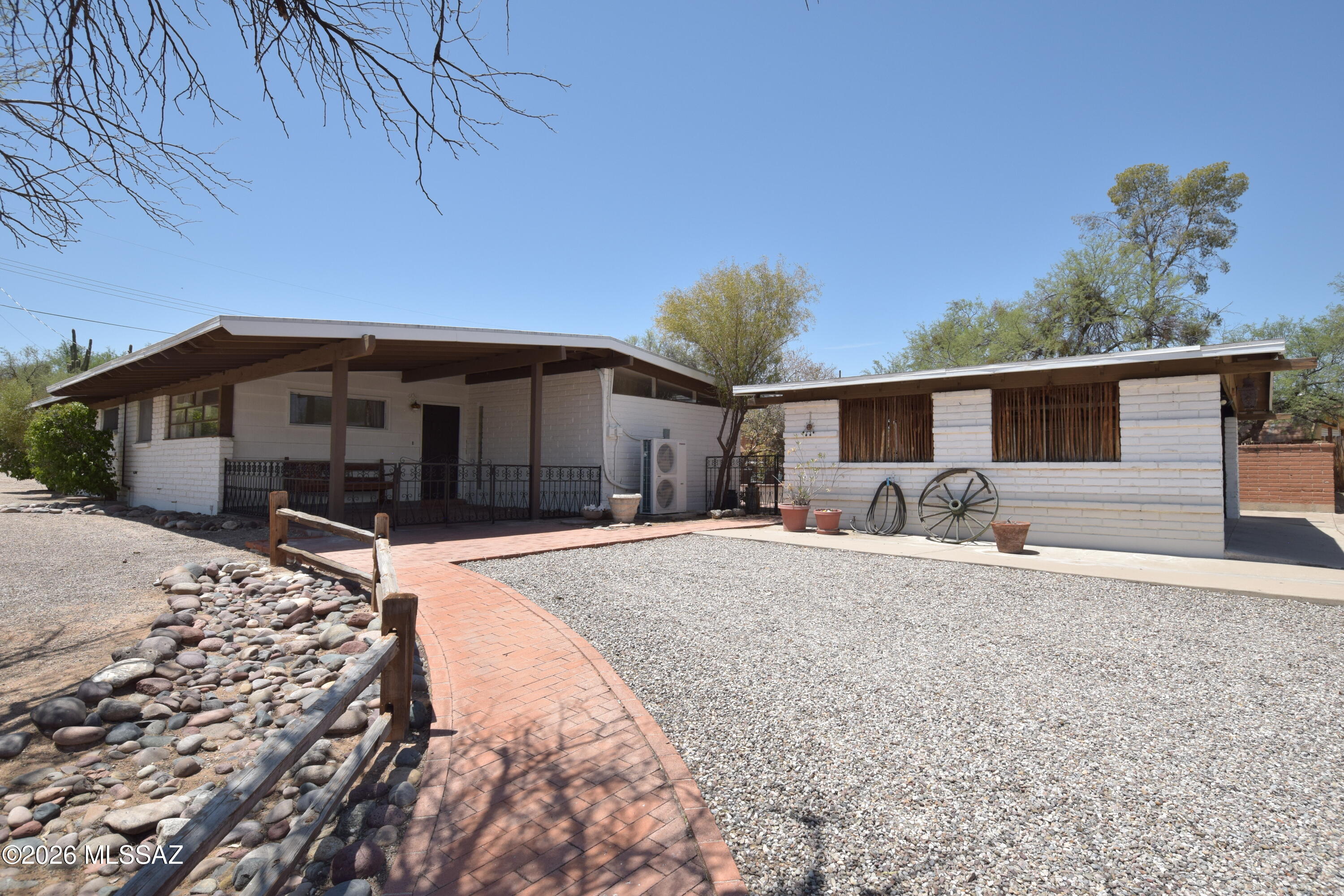 Discover this unique 1,985-square-foot single-family home situated on an expansive 0.67-acre lot in the scenic and sought after East Tucson Indian Ridge neighborhood. This spacious residence features four bedrooms and two bathrooms, beautifully finished with Saltillo tile and laminate flooring throughout and absolutely no carpet. The northern living area is highlighted by a grand clerestory window and a cozy pass-through fireplace, creating a bright and welcoming atmosphere. The kitchen comes fully equipped with a built-in wall oven, Corian countertops, and rich maple cabinetry, offering breathtaking mountain views right from the cooking and dining spaces. Operational convenience is built-in with central air conditioning and central heating systems, a hallway with multiple built-in storage areas, a functional hall bathroom featuring an updated tile surround, and a dedicated laundry area with a full-size washer and dryer included. Both west-facing bedrooms along with both living areas provide private, direct access to a massive multi-tiered fenced yard that showcases mountain vistas and includes all outdoor furnishings left for tenant use. The property includes a convenient two-space carport, and the pet policy welcomes dogs on a case-by-case basis with approval, though no cats are permitted on the premises. This home is offered as NON-SMOKING. The owner will retain full access of the attached storage unit.