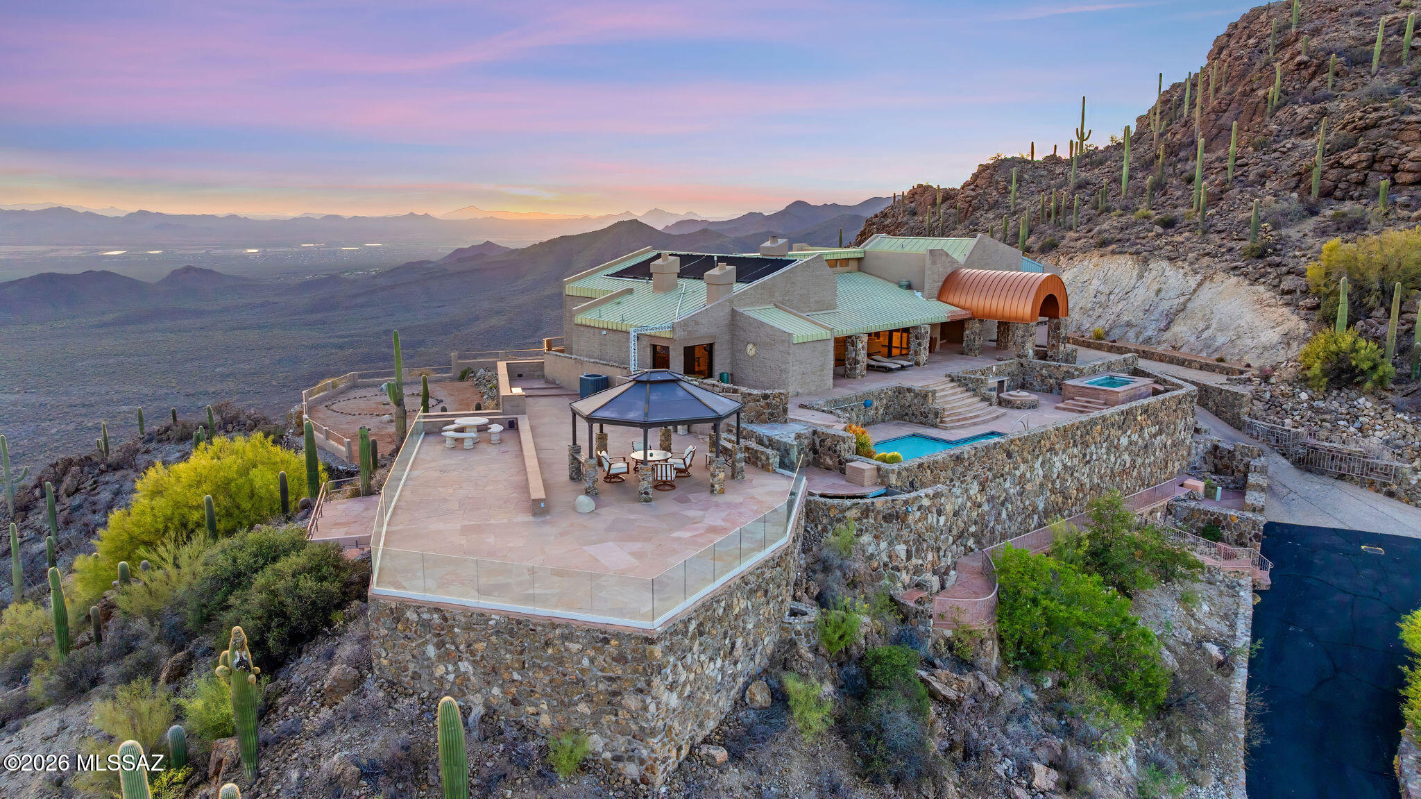 Tucson's Crown Jewel! A rare opportunity to own the highest home in the Tucson area with astonishing 360° vistas stretching 60 miles across the city and desert to the surrounding mountain ranges and beyond! Begin every morning with a brilliant sunrise emerging out of deep orange dawn glow. End every day with glorious sunsets over the Sonoran Desert, and behold the most dazzling sweep of city lights at night, with shining stars above. It's an unparalleled, constantly evolving, awe-inspiring display of color and luminosity you can experience from the comfort of your architect-designed, 4-bedroom, 5-bath home on 4 acres--smartly remodeled in 2024--with ultimate privacy, tranquility, and security behind three gates. This is the only home fully situated up on the crest of the Tucson Mountains, at almost 4000 ft elevation, a world away from urban bustle but only 20 minutes to downtown. The west side of the property borders the protected lands of Tucson Mountain Park, ensuring lasting peace and quiet with up-close views of rocky Tower Peak. The mountain ridge has its own pleasant micro-climate, 5-7° cooler than the city in summer with gentle warm desert evenings ideal for outdoor living and stargazing.

On approach, you pass through two successive gated entry points, then drive up the private road lined on both sides with beautifully crafted stone walls. Arriving at the estate, you'll be surprised, delighted, and uplifted by the expansive scenery, especially when a quick walk around the home reveals that the southern and western views are just as stunning as the eastern spectacle. The elegant split-face-block and stone house is surrounded by spacious flagstone and brick patios featuring wrap-around glass fencing for maximal sightlines. Enjoy the solar-heated pool and large built-in spa that can hold up to 10 people comfortably, as well as an open-air gazebo with mesmerizing vistas for shaded entertaining. The property features more than 100 saguaro cacti, visiting hummingbirds, soaring ravens, and the moon so big and close it feels like you can touch it.

The bright interior of the home features new LED recessed lighting throughout, all new appliances, and fresh flooring treatments (2024). You'll have a primary kitchen with additional kitchenette/wet bar, both of which open to a great room with wood-burning fireplace, cathedral ceilings, high clerestory windows, and a wall of glass framing stunning views of the Catalina Mountains and the city far below, which becomes a dazzling panorama of light at night. All 4 bedrooms have sliding-glass doors with patio or balcony access, creating a constant connection with the natural desert environment.

The primary bedroom features a stone fireplace and elegant en suite bath with an additional black-marble fireplace and spa tub with city and mountain views. A second extra-large bedroom at the opposite end of the house features its own city-view balcony with glass railing and a panoramic 9-ft-wide picture window looking west far across the desert.

The home has two independent HVAC systems (2023) for ample heating and cooling, augmented by mini-split HVAC units (2025) in the primary and west-facing bedrooms. The three-car garage has its own mini-split, toilet, utility sink, closet space, and refrigerator (2025). The gated entry features a new intercom system and security camera (2025).

Building a home in this magnificent location would be virtually impossible today, given current regulations and the significant cost of infrastructure, grading, and stonework. The benefits of many years of craftsmanship, engineering, and ingenuity are now yours to savor.

From this singular vantage point, many Tucson landmarks are in full view, including Mt. Lemmon (sometimes snow-capped in winter!), the Catalina Mountains, Saguaro National Park East, the University of Arizona, downtown Tucson, Golden Gate Mountain, and Saguaro National Park West, with Old Tucson and the Arizona-Sonora Desert Museum in the valley below. Farther west, you have a magnificent view of Kitt Peak and Baboquivari, the sacred birthplace of humanity in the Tohono O'odham tradition. This stellar property is so much more than a house--it's a precious opportunity to live at the scintillating intersection of desert, mountain, sun, and sky.