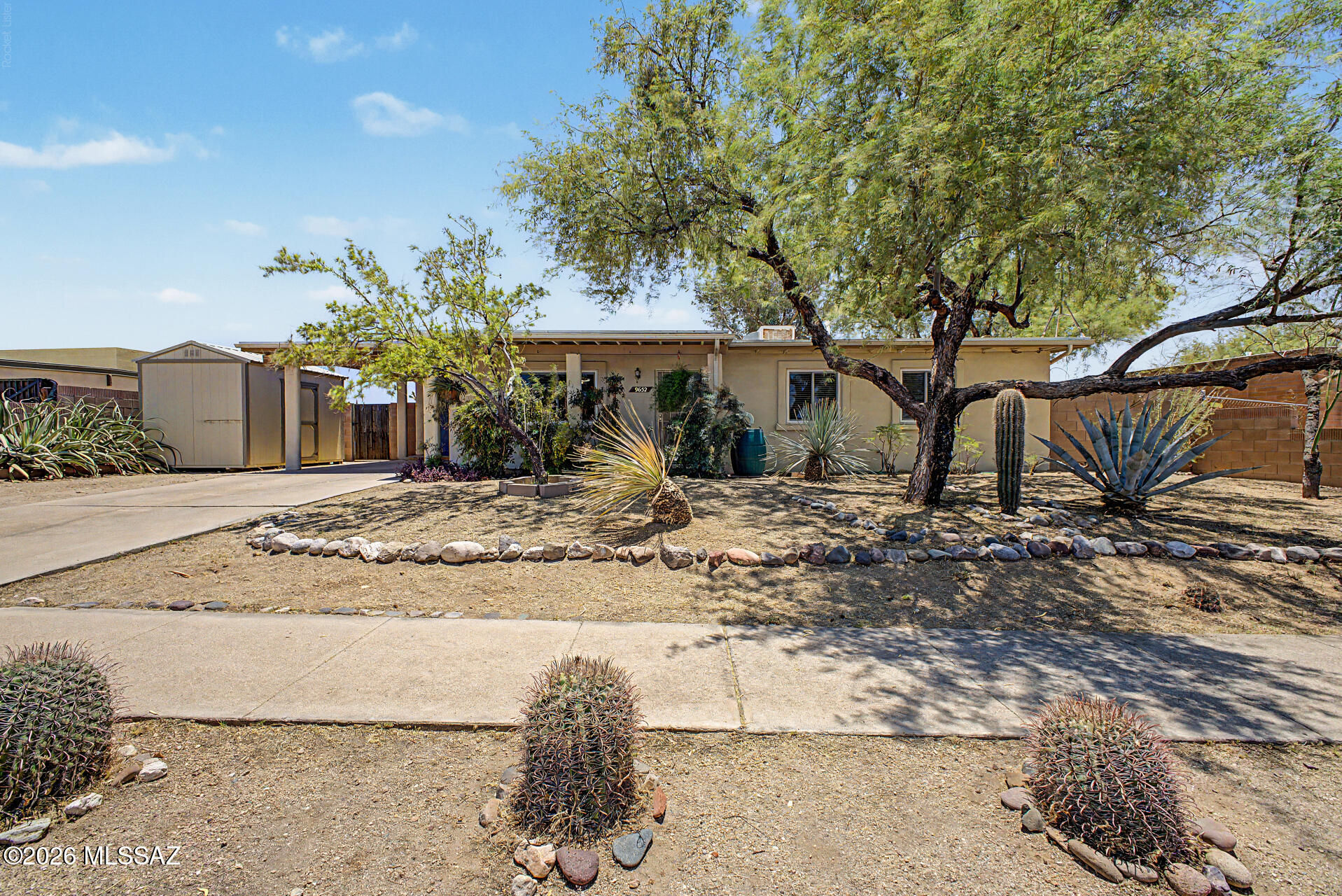 The search is finally over! This charming, well cared for slump block construction, 4-bedroom, 2-bath residence welcomes you with an attached carport, a storage shed, mature shade trees, water harvesting and a low-maintenance desert landscape. 1yr old AC system & all newer windows. Inside you'll find a serene living/dining rm w, natural light, neutral colors, ceiling fans, blinds, & durable 18' tile flooring. Kitchen comes with ample counter space, wood cabinetry, a pantry, & essential built-in appliances. The main bedrm includes plush, NEW carpeting, ceiling fan & a private bathrm.  Private, walled in backyard w/ plenty of space for outdoor relaxation & mature trees that provide natural shade. Gutters & water tanks convey for water harvesting & low water bills. Grey water system included. NO HOA! NO neighbors behind this lot - creating lots of privacy.  10 year warranty on brand new AC system.  Large laundry room with sink and washer included - separate building behind carport. 
Quiet, peaceful street.  The home was just deep cleaned professionally before listing for sale for relaxation and easy move.