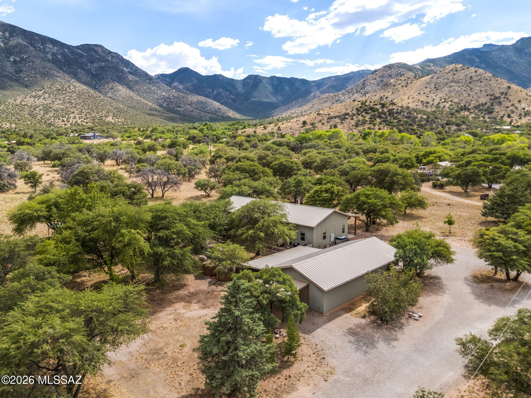 Custom home on 2+ acres with breathtaking Miller Peak views and adjacent to National Forest. Built in 2017, this 2100 sqft home features 3 beds, office, 2 baths, 12' ceilings, expansive windows, wood and tile flooring, handcrafted native wood cabinetry, a custom kitchen island, and a cozy Quadrafire wood stove. Enjoy the extended covered front porch, private courtyard, fenced garden/orchard, mature oak trees, and abundant wildlife. The impressive 1270 sqft shop/garage offers 220 outlets, welder/kiln hookup, oversized doors, and additional covered work/storage areas. Property includes a private solar well, extensive rainwater harvesting systems, Liberty water, 400 amp service, metal roofs, NO HOA, and Firewise wildfire protection measures throughout. A truly spectacular Hereford, AZ gem!
