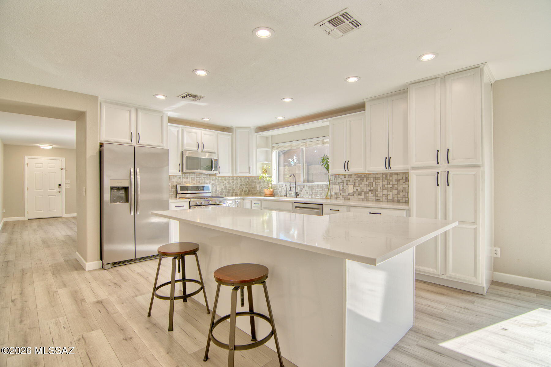 Beautifully remodeled 4br/2ba home in NW Tucson, move-in ready with modern upgrades throughout. Renovated in the last year with new luxury vinyl plank flooring, carpet in 2 bedrooms, fresh interior paint, and 4'' baseboards. Light, bright open layout with living & formal dining. Updated kitchen opens to family room and features large island, breakfast bar, white cabinets, backsplash, new sink/faucet, and stainless appliances with gas range. Split bedroom floorplan. Spacious primary suite with walk-in closet, dual sinks, and tiled walk-in shower with rainfall head. French doors lead to low-care backyard with pergola patio. Laundry room, ceiling fans, and 2-car garage.