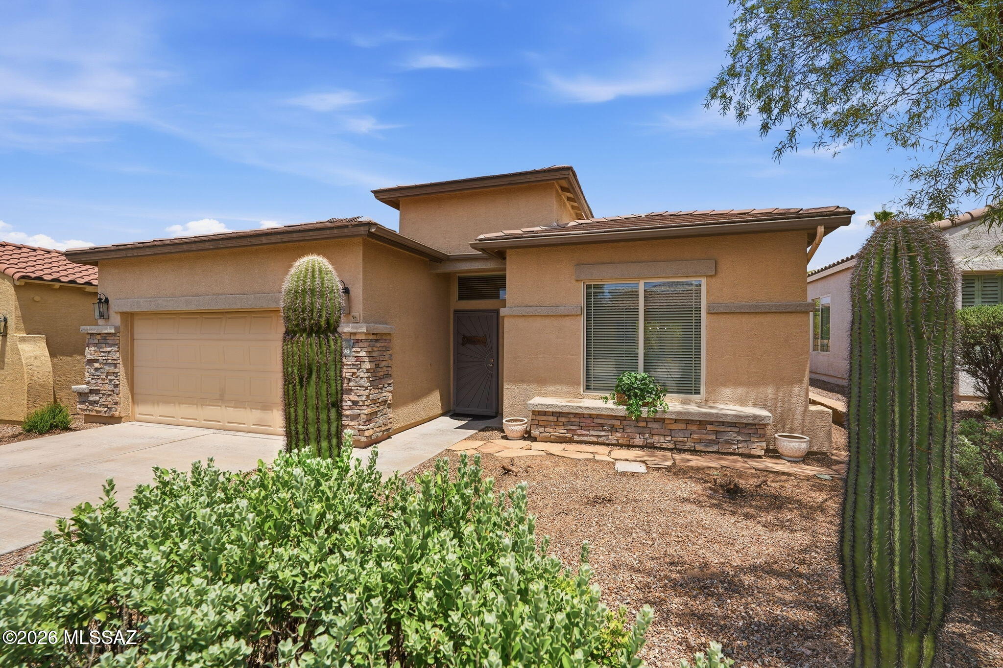 Welcome to this warm and inviting 2,040 sq ft single-level home, where comfort meets easy desert living! Inside, you will find a bright, move-in-ready layout featuring durable ceramic tile in the main living areas and cozy carpet in all three bedrooms. One guest bedroom even includes a built-in wall bed, making it perfect for overnight visitors or a home office.  The heart of the home is the lovely kitchen, showcasing gorgeous granite countertops, a pantry, a cozy breakfast nook, and its own beverage fridge. Unwind by the natural gas fireplace in the living room, or retreat to the primary suite, which offers dual sinks, a separate shower, and a relaxing garden tub. There is also a convenient laundry room and the washer and dryer are included! Step outside to your private backyard oasis, where a large, covered patio opens to lush turf grass, mature shrubs, a soothing water fountain, and a mature navel orange tree. Nestled in a friendly Eastside neighborhood with paved streets and sidewalks, this home is just minutes from shopping and dining. Plus, the 2-car garage features handy, built-in cabinets.