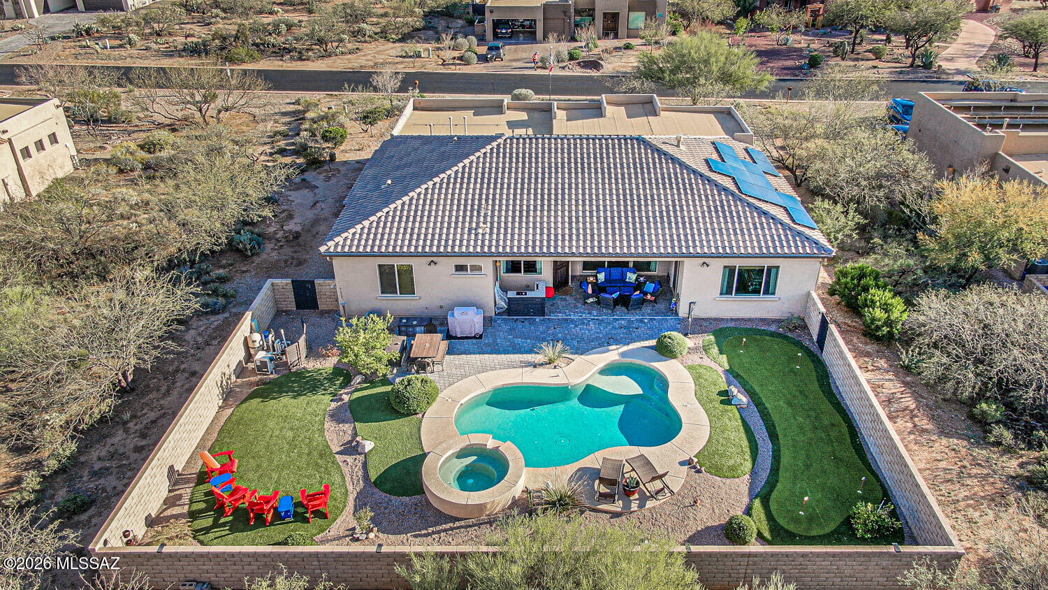 Located in the exclusive gated residential community of Stone House, this home checks all the boxes! Santa Fe style with stone facade, the home features 4 bedrooms, 2.5 baths, a pool/spa and a putting green!  The open great room floor plan is perfect for that busy family or for entertaining. Cherry cabinetry throughout, granite counter tops, Life Source whole house water system, Smart thermostats. The kitchen features a large island which is also a breakfast bar, bottom rollout shelves, Frigidaire French Door 2 drawer refrigerator, built-in wine refrigerator, a HUGE pantry.  Tile throughout except for the den and bedrooms. There is a triple sliding glass door off the great room to the back. The entry and back door feature custom wrought iron security doors. The den has views of the Santa Rita Mountains and built in cabinetry on 2 walls. The three bedrooms on the east side of the house share a large bathroom with a double vanity.  The middle bedroom has built in shelving. The large laundry room has high end Samsung steam, "smart" washer and dryer.  Plenty of room in the garage for storage, golf cart, bikes; there is even space for a work area, and includes an electric car charger. Home Warranty by First American Home Warranty.