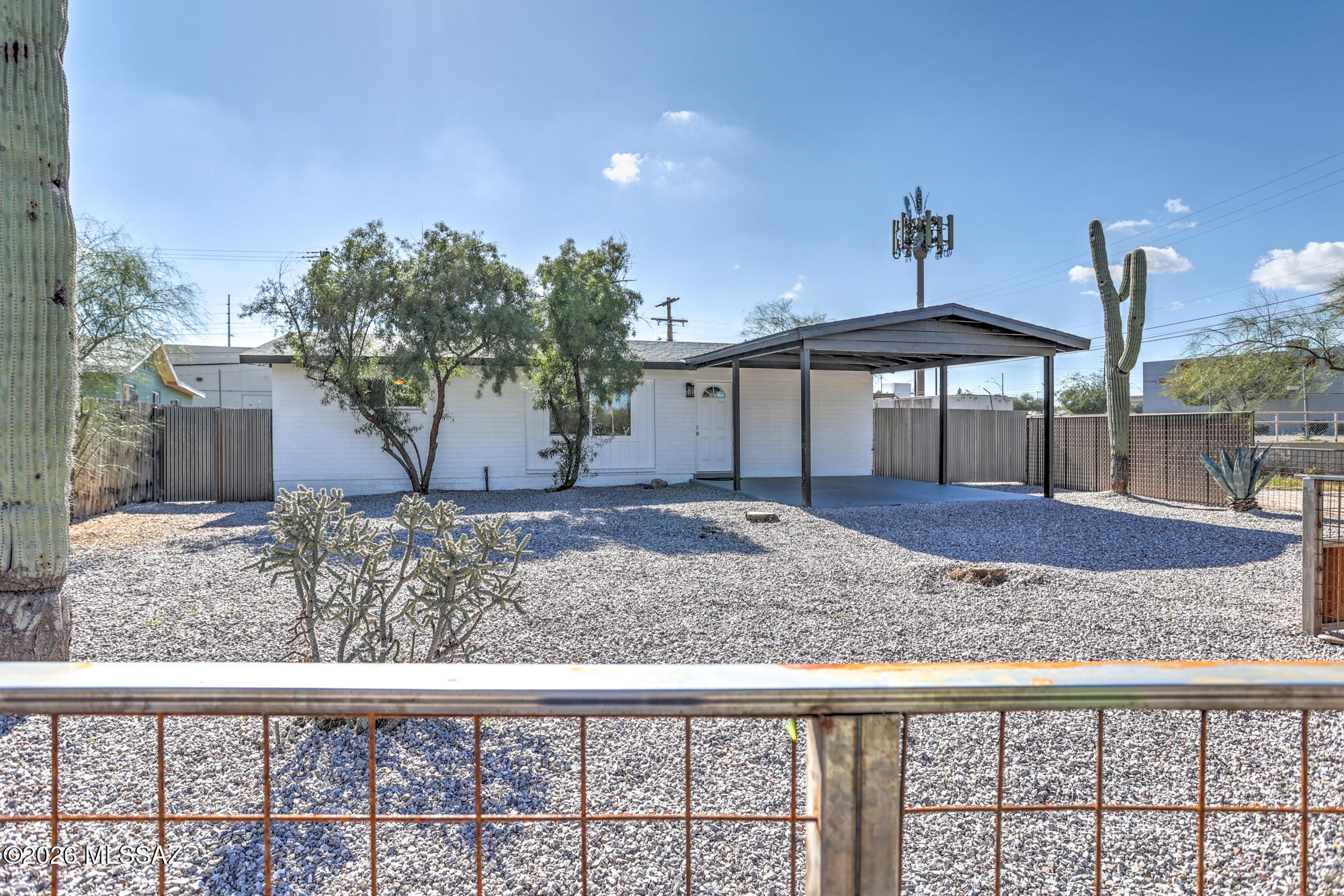 Seller will accept or counter offers in range 299,900 to 324,900-  Adorable classic red brick ranch home on fully fenced and gated large outside corner lot in about a 10 min proximity to the U of A.  Rustic metal fence design has a double gate entry and oversized carport which easily doubles as a front patio with mountain views!  Fully remodeled interior with tile floors throughout (no carpet), new kitchen and baths, new dual pane windows and doors, both interior and exterior plus new trim and baseboards throughout.  New cabinetry, stainless steel appliances, butcher block countertops, all new lighting, brand new upgraded electric panel, new roof, HVAC & mechanicals.   Desirable split bedroom floorplan.   Huge backyard with a 2nd drice through gate and ramada structure for additional shade or additional parking off street and behind the fence.  Nice amount of mature landscape including a huge gorgeous saguaro!  Locking storage off back.  Stacked laundry in kitchen.   Window blinds and Ceiling fans throughout.   New shingle roof, in warranty!