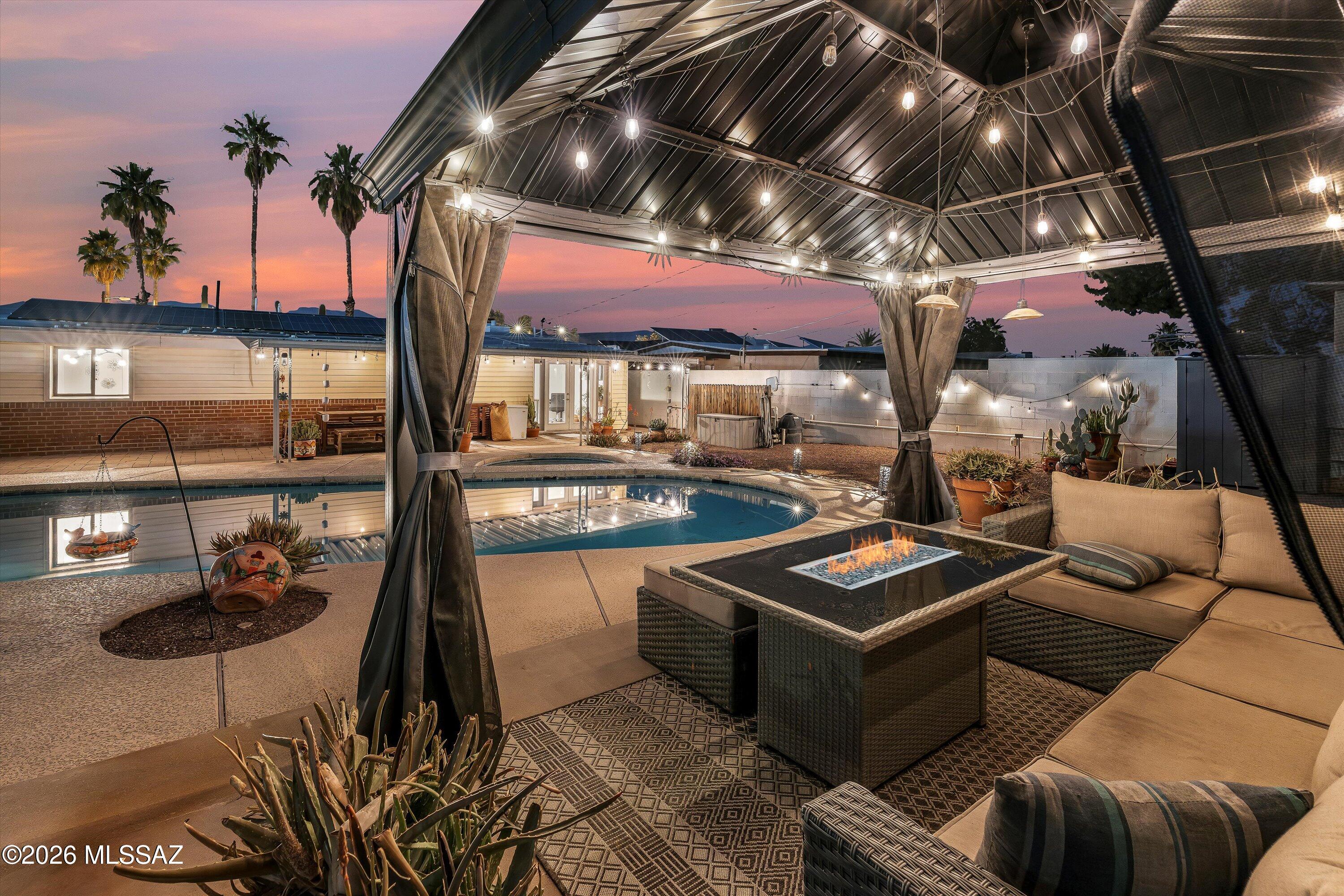 Truly gorgeous and full of charm, this unique mid-century home is an entertainer's dream. The deep, long, oversized diving pool features dual entry steps, can be heated for year-round use, and includes a spa--newly refilled and ready for magical nights out back. Multiple entertaining areas await: a gazebo, grill space, and lush greenery everywhere. A green thumb's paradise--plants can convey!
No HOA. In addition to the RV gate with secure off-street parking for a 40+ft. rig, there is a half-circle driveway plus carport so there's plenty of space for your toys. Low, fixed-rate leased solar that won't escalate--far less than most electric bills.

Inside, stunning décor with gorgeous, well-cared-for wood beam ceilings, unique lighting, and modern updates throughout. The front 3 bedroom / 2 bath includes an ensuite primary along with neat pass-through oversized bedroom storage. Back suite functions as a private guest quarters or second primary. Office overlooks the beautiful backyard.

Mountain and city views, centrally located in the sought after Mitman neighborhood. Close to shopping, medical, schools, the UofA, TMC, the Loop, transit and 3rd St bike path; this fun & stylish home is unforgettable, see it for yourself!