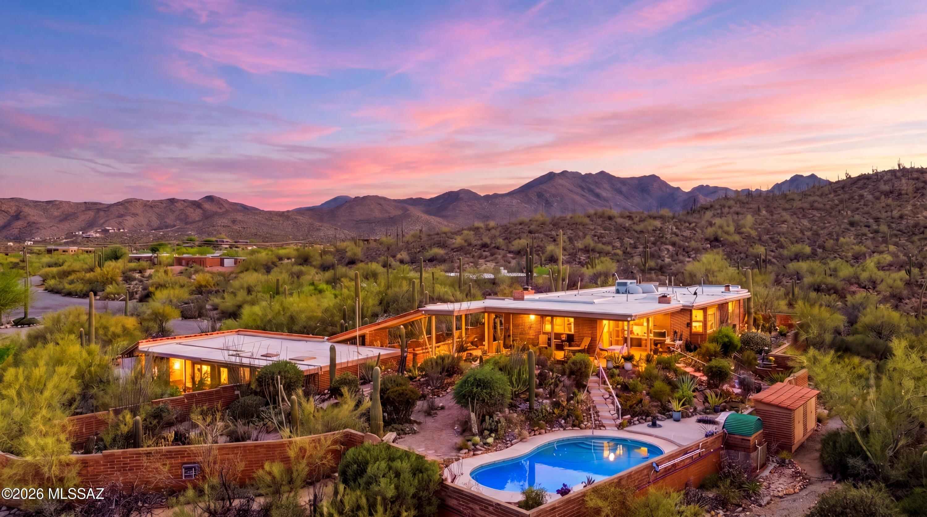 Perched on over an acre on one of Tucson's most breathtaking view lots, this exceptional Westside retreat captures the true beauty of the Sonoran Desert. Nestled against the rugged ridgelines of the Tucson Mountains, this gated property offers unobstructed panoramic views stretching across three mountain ranges, sparkling city lights, and endless desert horizons. Every window was thoughtfully positioned to frame the surrounding natural beauty, creating a living experience where the views become part of the home itself.
The turnkey main residence features 3 bedrooms, 2 bathrooms, and warm architectural character throughout, including stunning tongue-and-groove ceilings in the dining area, a welcoming wet bar in the living room, and an inviting floorplan designed to embrace indoor-outdoor living. The spacious guest bedroom includes a built-in Murphy bed and private patio access, offering flexibility for guests, work, or multigenerational living. A detached office/studio space provides the perfect setting for a creative retreat, home office, gym, or flex space.
Step outside to experience resort-style desert living at its finest. The elevated pool overlooks sweeping mountain and city views, while expansive covered patios, a large front porch, and winding walking paths throughout the property create endless spaces to relax, entertain, and take in Tucson's unforgettable sunsets. The oversized 2-car garage includes a substantial storage room with plumbing already in place, offering incredible potential for expansion or customization.
Located just minutes from downtown Tucson, the University of Arizona, shopping, dining, and outdoor recreation, this rare desert sanctuary combines privacy, convenience, and some of the most dramatic scenery Tucson has to offer.