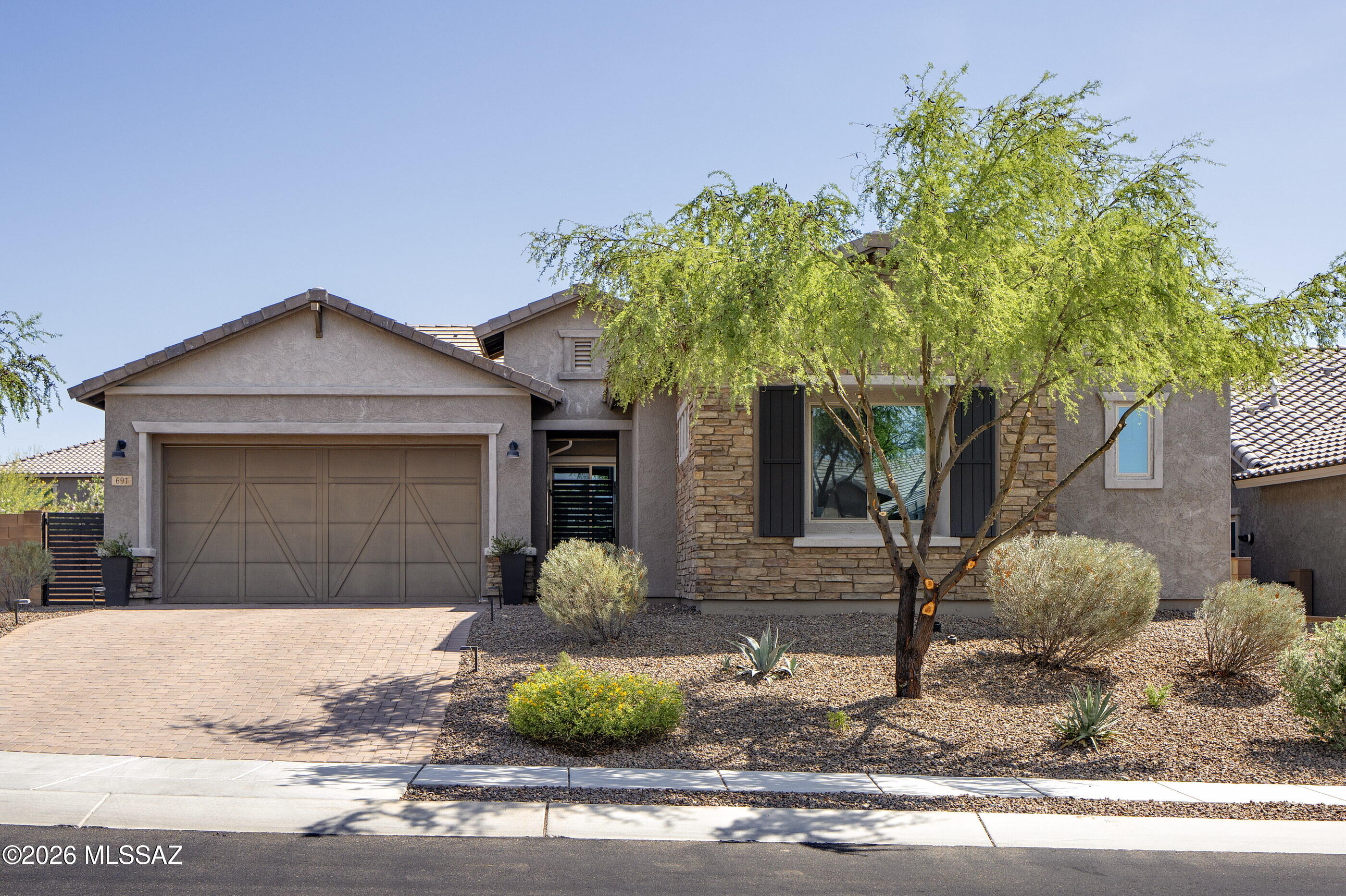 Tucked away on a cul-de-sac in the sought-after Valley Vista neighborhood of Rancho Vistoso, this beautifully appointed Pulte residence offers a seamless blend of comfort, style, and desert serenity. A private courtyard entry sets a welcoming tone, leading into light-filled interiors where soaring ceilings, luxury plank tile flooring, and an open-concept design create an atmosphere that is both sophisticated and inviting. The heart of the home is a spacious kitchen featuring a generous center island, walk-in pantry, and casual dining nook with direct access to the outdoor living spaces. Open to the great room and dining area, it serves as the natural hub for everyday living and effortless entertaining. Thoughtfully designed with a split-bedroom floor plan, the primary suite occupies its own private wing, offering a peaceful retreat complete with a spa-like bathroom, quartz countertops, walk-in shower, and expansive closet. On the opposite side of the home, three additional bedrooms provide flexibility for family and guests, including a private en-suite bedroom and a versatile bonus space ideal for a home office, media room, or fitness studio.

Outside, the backyard embraces the beauty of the surrounding landscape. A covered patio extends the living experience outdoors, where sweeping mountain views provide a stunning backdrop for morning coffee, evening sunsets, and gatherings around the fire pit. Low-maintenance and thoughtfully designed, the outdoor spaces invite year-round enjoyment of Southern Arizona's exceptional climate.

Combining modern comfort with a coveted Rancho Vistoso setting, this residence offers an elevated lifestyle in one of Oro Valley's most desirable communities.