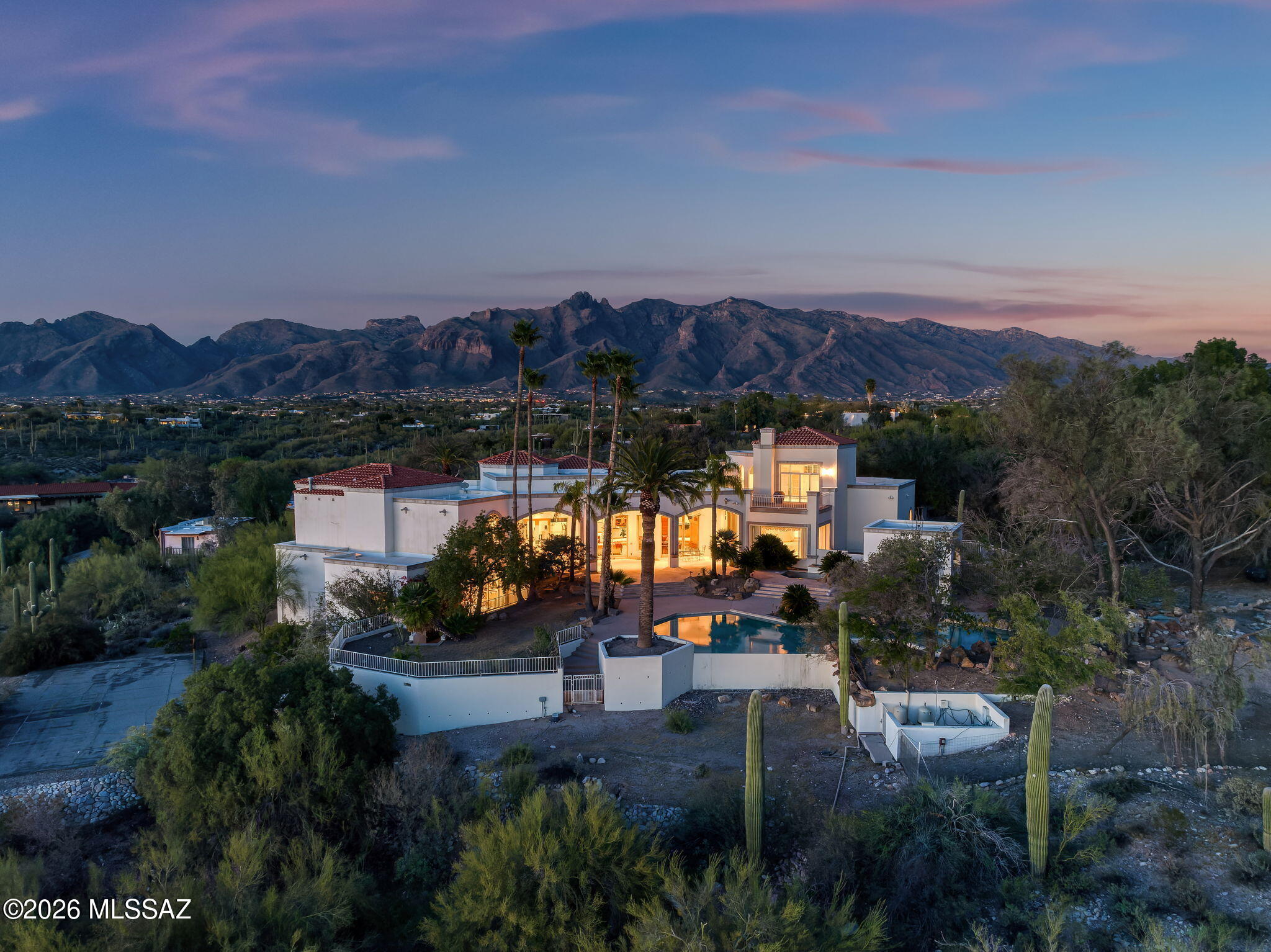 Privately gated and set behind a long, winding driveway, 5151 N Calle Ladero is a remarkable Catalina Foothills estate offering exceptional privacy, expansive living, and breathtaking views across 4.32 acres of pristine Sonoran Desert landscape. Perched high in one of Tucson's most prestigious foothills locations, this 8,138-square-foot residence blends grand architecture, luxurious amenities, and serene desert surroundings. From the moment you enter the private gates, the property unfolds into a secluded retreat surrounded by mature desert landscaping, natural rock features, and sweeping views of the Santa Catalina Mountains and Tucson city lights. Inside, soaring ceilings, abundant natural light, and expansive living spaces create a dramatic, yet welcoming environment designed for both elegant entertaining and comfortable everyday living.

The thoughtfully designed floor plan includes 7 bedrooms and 7 bathrooms, featuring private downstairs guest quarters ideal for multi-generational living, long-term guests, or live-in accommodations. Multiple gathering areas, high ceilings, and large windows frame the surrounding desert and mountain vistas throughout the home. A wet bar enhances the entertaining experience, while a cedar-lined wine cellar and storage room provide both luxury and practicality.

The spacious primary suite offers a private retreat, complete with a secluded courtyard off the primary bathroom, creating a tranquil indoor-outdoor experience. An upstairs bedroom with private balcony captures stunning mountain and city views, adding to the home's elevated foothills appeal.

Outdoor living is equally impressive, featuring a huge resort-style pool with waterfalls, expansive patios, and beautifully integrated desert landscaping. The grounds offer exceptional privacy and multiple spaces for relaxing, entertaining, and enjoying Tucson's spectacular sunsets and star-filled skies.

The estate also includes a three-car garage, generous additional parking, and extensive storage, making the property both functional and luxurious.

Adding significant value and flexibility, the property includes two additional vacant parcels:
Parcel 108-15-048U (2.11 acres) and Parcel 108-15-048R (1.02 acres) -- bringing the total acreage to 4.32 acres. These additional parcels preserve privacy in one of Tucson's most sought-after areas.

Located within the highly regarded Catalina Foothills School District, this estate is just minutes from La Encantada, La Paloma Country Club, the Campbell Corridor, and premier dining, shopping, golf, and hiking. The property also offers convenient access to the University of Arizona, downtown Tucson, and many of the Foothills' most desirable destinations.

5151 N Calle Ladero is a rare privately gated Catalina Foothills estate offering expansive luxury living, breathtaking views, and 4.32 acres of exceptional privacy -- an extraordinary opportunity in one of Tucson's most coveted locations.