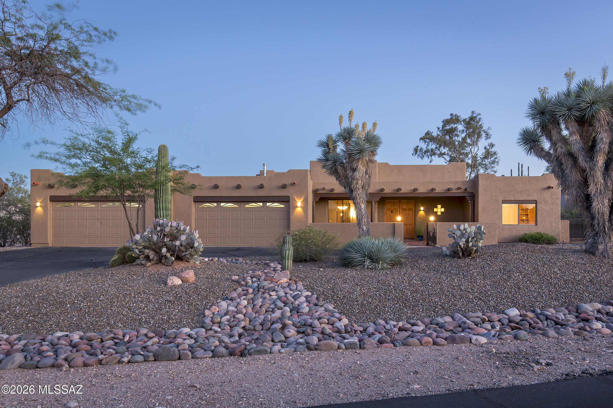 Welcome to a private desert retreat in the gated community of Los Arroyos Del Oeste. Set on 1.14 acres , this exceptional custom Santa Fe home seamlessly blends timeless Southwestern architecture with resort-style living.

Inside, the dramatic great room is anchored by soaring 14-foot ceilings and a classic kiva fireplace, creating a warm yet impressive gathering space. The open-concept kitchen features granite countertops, abundant cabinetry, and a breakfast nook, while the formal dining room and built-in wet bar make entertaining on any scale effortless.

Designed with both comfort and flexibility in mind, the split four-bedroom floor plan offers exceptional privacy. The spacious primary suite is a true escape, complete with a spa-inspired bath featuring a soaking tub, separate showe dual vanities, a generous walk-in closet, and direct access to the backyard oasis. A fourth bedroom is perfectly suited for guests, multigenerational living, a home office, or an art studio.

An oversized four-car garage is a rare and highly desirable feature, providing abundant room for vehicles, recreational equipment, a workshop, hobbies, or extensive storage.

The backyard is designed to feel like your own private resort. A sparkling Pebble Tec pool and spa with a cascading waterfall serve as the centerpiece, complemented by a beehive fireplace, outdoor kitchen with a built-in natural gas BBQ, polished concrete bar, and expansive wood-beamed covered patio. Multiple seating areas, mature desert landscaping, towering saguaros, and a fully walled yard create an inviting setting for entertaining or simply enjoying Arizona's spectacular sunsets.

Offering privacy, craftsmanship, generous living spaces, and unforgettable outdoor amenities, this is a home that captures the very best of Tucson living.