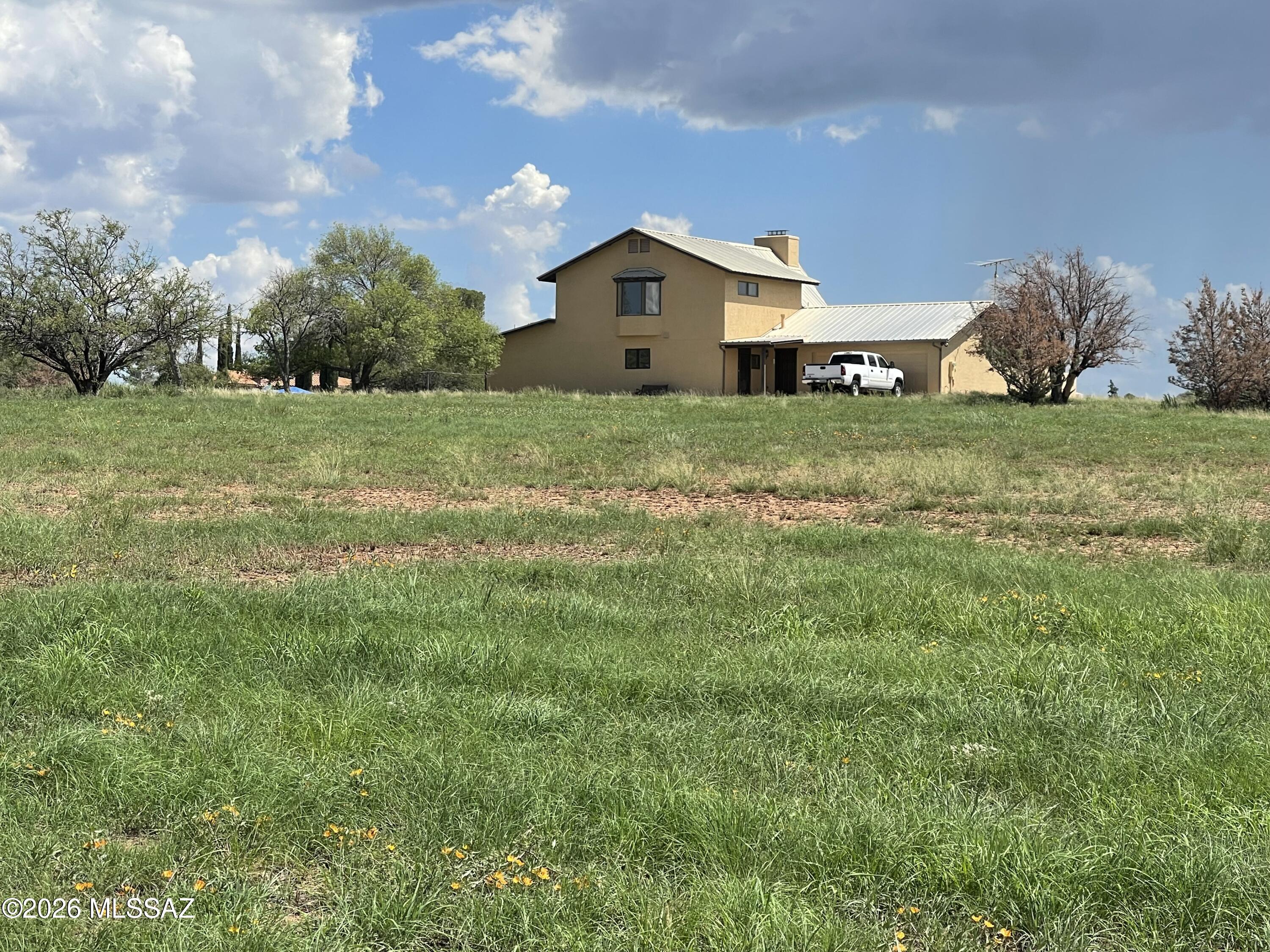 Custom home built on 10+ acres with old oak trees and native grass. The home has new exterior paint, new carpet, new tile in bathroom, and new stove in kitchen. Open wood truss ceiling and large windows in the great room with a big cozy fireplace,  bedroom/office downstairs is large enough to make into a third bedroom. Loft and primary bedroom upstairs with en-suite, and walk-in closet w/cedar. Two car garage has utility area and laundry. Outdoor block structure with roof could be for animals, or storage. Amazing views of the Santa Rita Mountains, Great location, close to town center and restaurants. National Forest just down the road for riding, and hiking. Easy commute to Tucson, Nogales, & Sierra Vista. +++Extra land  adjacent to this property can be bought, 8.95 acres for $175,000