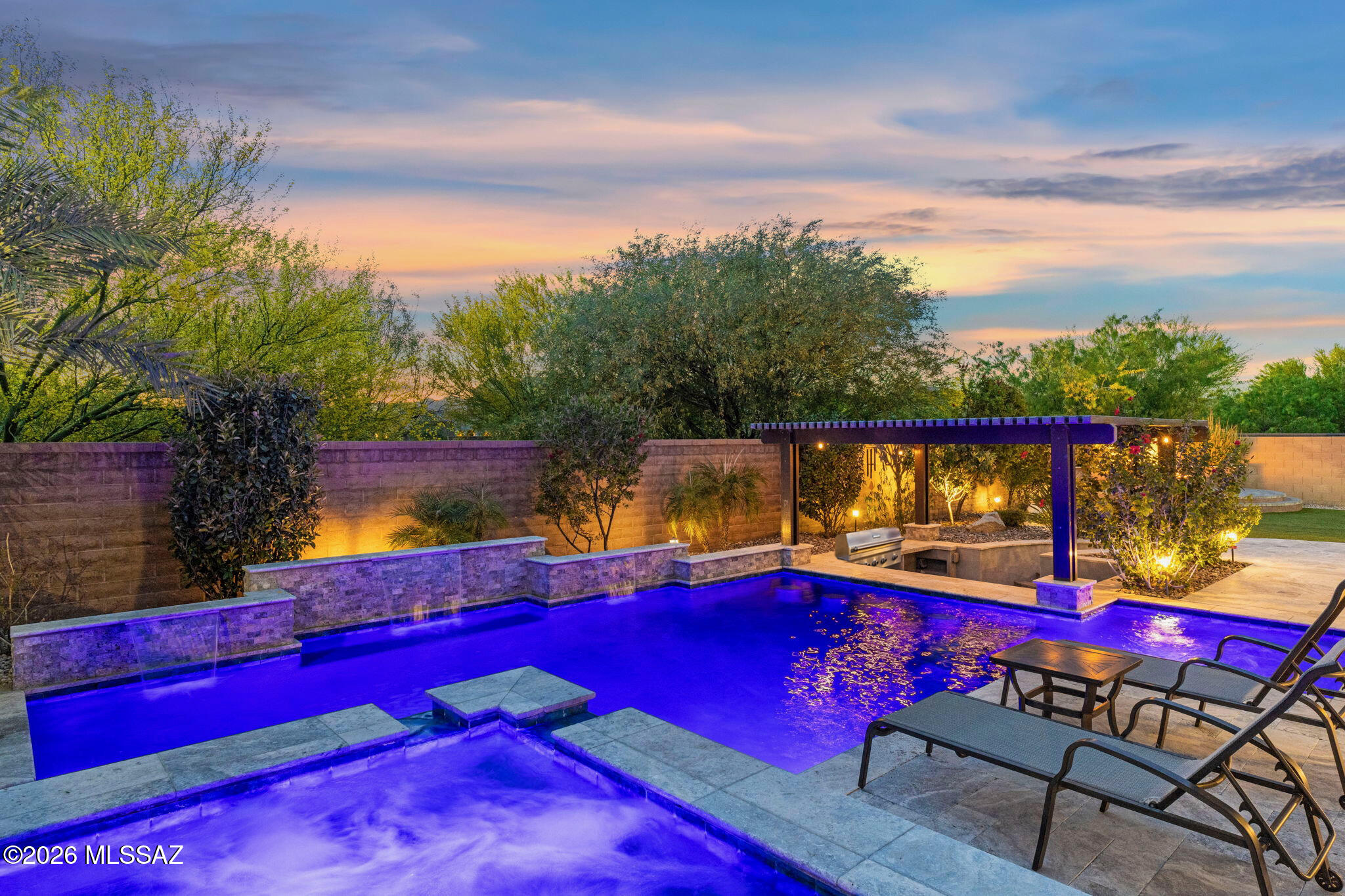 Experience true resort-style living with a custom Pentair Presidential pool and spa, seamless indoor-outdoor design, and a fully owned ~10 kW SolarEdge system delivering exceptionally low energy costs. Located in sought-after gated Center Pointe Vistoso, this home offers the perfect blend of luxury and everyday comfort. Soaring ceilings and abundant natural light highlight an open, airy layout with refined finishes, smart home features, surround sound, and three-zone climate control. Expansive sliding doors open to a private backyard retreat featuring swim-up bar stools, a sunken outdoor kitchen, firepit, and multiple lounge areas surrounded by lush landscaping for exceptional privacy and stunning mountain views. Community amenities include a heated pool, spa, grilling areas, firepits, and expansive green space.