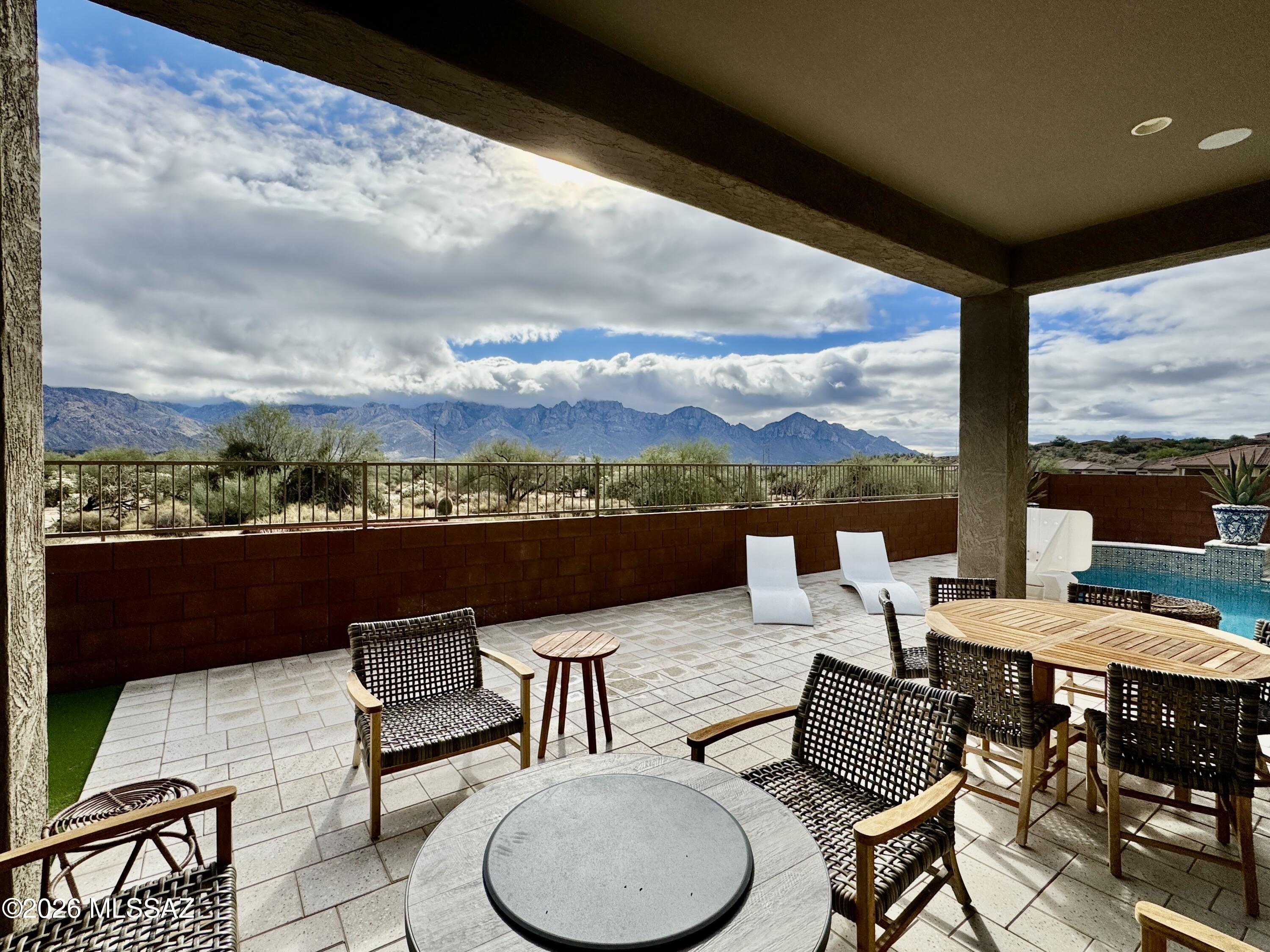 Welcome to your private desert oasis nestled within an exclusive gated community in the heart of Oro Valley. Built in 2020, this spectacular estate has served strictly as a lightly-used second home, with the owners averaging just two weeks of occupancy per year. Offering the rare opportunity to own a property in absolute pristine, immaculate condition, this home seamlessly combines sophisticated modern upgrades with breathtaking, unobstructed views of the desert and the Catalina Mountains. From the moment you arrive, the grand curb appeal captivates you with an elegant, premium paver driveway and walkway that extends into a private front courtyard. Pass through the oversized, decorative iron security door into a light-filled interior boasting soaring ceilings, an airy open-concept volume, and a highly desirable split-bedroom floor plan that ensures maximum privacy.
 
The gourmet chef's kitchen is a design masterpiece, showcasing upgraded leathered quartz countertops, custom above-cabinet and under-counter lighting, a premium Whirlpool® stainless steel appliance package with a gas cooktop, and a highly coveted pot filler. Storage is effortless with a spacious walk-in pantry, while the automated remote-controlled kitchen blinds, dual wine/beverage refrigerators, and a Bluetooth-enabled whole-home surround sound system elevate your daily living and entertaining experience.
 
Retreat to the luxurious primary suite, where a massive walk-in closet with custom shelving features a rare, direct-access door leading straight into the upgraded laundry room (complete with built-in folding table, storage cabinets, and a Whirlpool washer/dryer package). The spa-like primary bathroom boasts a massive walk-in shower with dual shower heads, a rain shower head, and a custom tiled poured pan. Two additional guest bedrooms each feature their own generous walk-in closets, with timeless plantation shutters and ceiling fans installed throughout the entire home.
 
The backyard is a resort-style masterpiece designed to maximize Arizona's indoor-outdoor lifestyle. Step out onto the extended travertine paver patio to take in the dramatic, panoramic mountain and desert views over the fully fenced yard. Perfect your short game on your private putting green, or unwind by the heated pool, which features tranquil waterfalls, custom upgraded tile work, and effortless remote-controlled lighting and temperature automation. When you need a break from the afternoon sun, a remote-controlled screen rolls down to shade the oversized patio doors. For the ultimate entertainer, the front courtyard features a dedicated gas line for grilling under the ambiance of exterior string lights, and the fully loaded garage includes a secondary refrigerator, a standalone freezer, and a bonus mini-fridge.
 
A rare gem of a property where luxury, privacy, and flawless condition meet. This is a must-see!