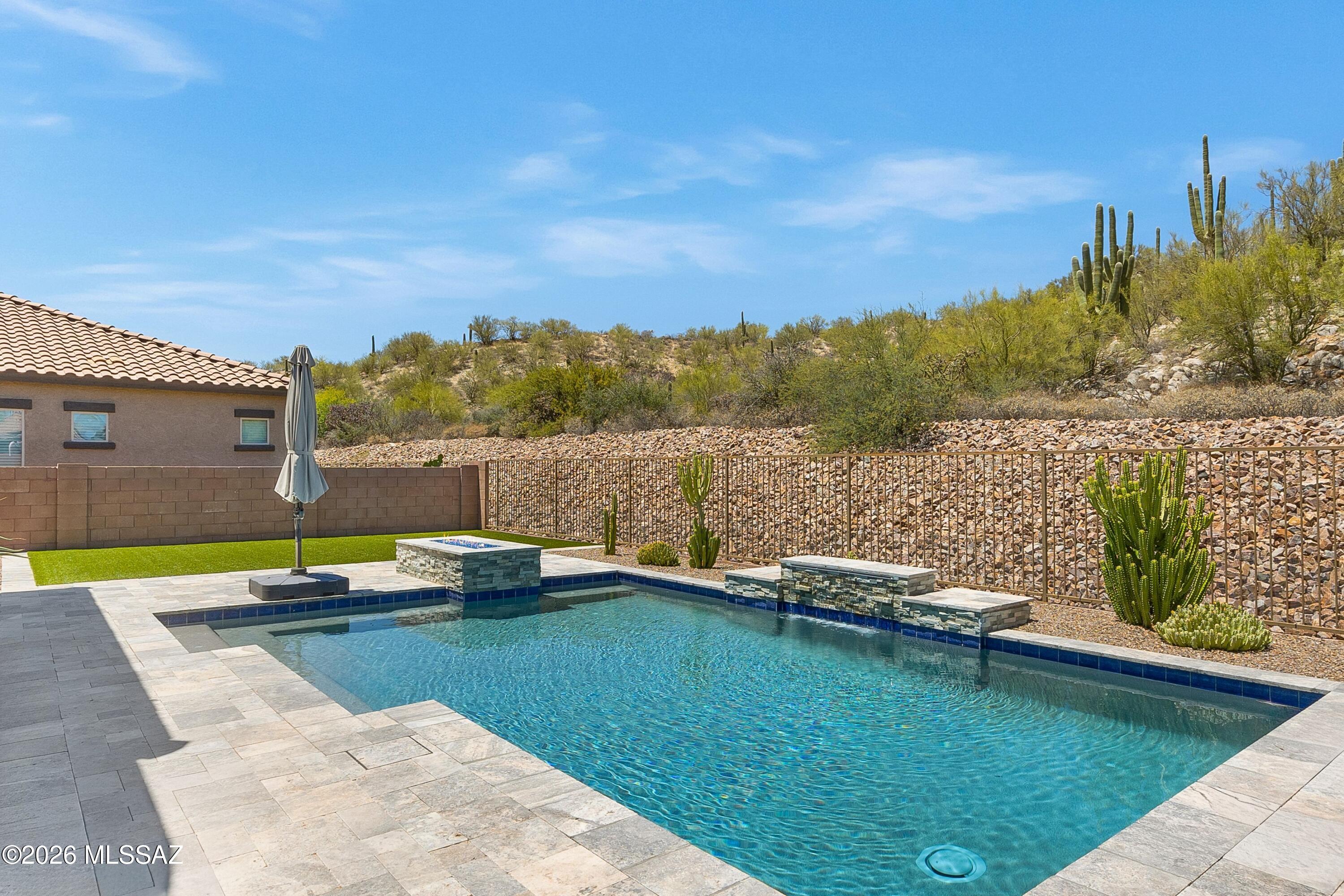 Located in the heart of Oro Valley in a small, gated community - Alterra at Vistoso Trails; 13477 N Mariposa Lily Drive offers residents a move-in-ready home with excellent amenities close by. Situated on a north facing lot backing up to a saguaro studded hillside, the setting is private. Built in 2021, the property has been enhanced by the owners and is in immaculate condition. The 2,488 sq ft floor plan is optimally designed for flow and function with 4 bedrooms, 2 ½ baths, plus a private office over a split floor plan. Features throughout include; tile flooring, white shaker cabinetry, quartz countertops, tiled showers, designer lighting, and 8 ft upgraded interior doors. The kitchen is complete with stainless appliances, a farmhouse sink, walk in pantry and under cabinet lighting. Double sliding doors in the great room seamlessly connect the indoor and outdoor spaces. Fully outfitted for desert living, the backyard has been finished with a custom heated swimming pool, complete with a fountain and fire feature. The shaded covered patio and pool surround feature white travertine decking, with a pop of green from thoughtful plantings and a spacious zone with synthetic grass.

The garage has been extended by 4 ft providing ample room for vehicles and storage.

Within the community, there are sidewalks, a lovely park, desert trails and access to a paved multi-use path for walking, running or cycling. 

Outside of the neighborhood the Oro Valley lifestyle awaits. Nearby, there are highly rated schools and excellent parks. Wide cycling lanes connect to "The Loop" multi-used paved path system. Within a short radius, you will find Oro Valley Hospital & Medical Center, Oro Valley Marketplace (shopping, dining & more), world-class hiking trails, and high quality singletrack for mountain biking.