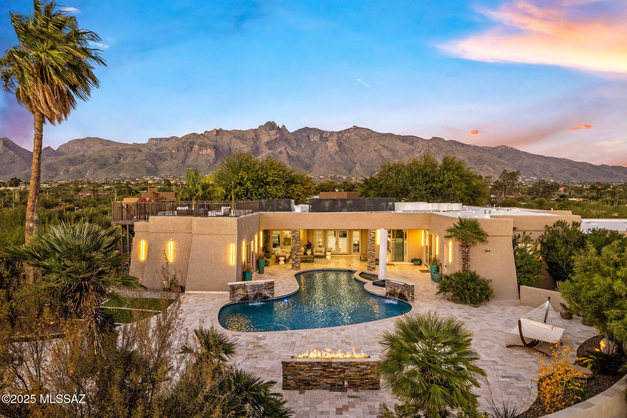 The Campbell Estate- Modern Spanish Colonial estate in the heart of the Catalina Foothills, situated on a classic 1.21 acre masonry homesite. Experience bespoke luxury at every level in this sophisticated 6,700 sq. ft. compound, known as The Campbell Estate, where you can be the second owner of this meticulously redesigned masterpiece.
Nestled at the end of a private enclave of only seven custom homes and protected by two automatic gates, this estate combines privacy with elegance. From the moment you arrive, the extraordinary paved entry courtyard, tranquil spillway fountain, and lush, mature landscaping set the stage for the refined lifestyle within. Tall doors and high ceilings create a seamless flow throughout the interior, while strategically placed windows capture stunning city lights and mountain vistas.

The gourmet kitchen is a showpiece, featuring a 10' oversized quartz double-waterfall island, custom knotty alder cabinetry, dual electric ovens, dual dishwashers, dual sinks, two refrigerators, a full wine fridge, a 6-burner gas cooktop, and a full-size butler's pantry with a desk area. Each of the six ensuite bedrooms offers walk-in closets. The primary suite boasts a fireplace, sitting area, private office, French doors opening to an inner courtyard and pool/spa, and a luxurious bath with a soaking tub framed by floor-to-ceiling windows, plus double rain showers.
Car enthusiasts will love the 6-car garage with two electric car jacks, while guests can enjoy the flex quarters with a mini-kitchen, ideal as spa/exercise space or additional lodging. Outdoors, a resort-style pool and spa oasis awaits, surrounded by travertine pavers, fountains, a full high-end kitchen, generous turf area, fire pit and a rooftop deck offering jaw-dropping panoramic views.

Every detail has been thoughtfully updated: travertine and wide-plank wood floors, 3 HVAC systems, roof, drywall and insulation, modern light fixtures, high-tech CCTV, and fully permitted inspections.
Perfectly located near La Encantada, St. Philip's Plaza, downtown Tucson, golf, hiking, and the University of Arizona, with highly sought-after District 16 schools, this estate offers the ultimate combination of privacy, luxury, and convenience
