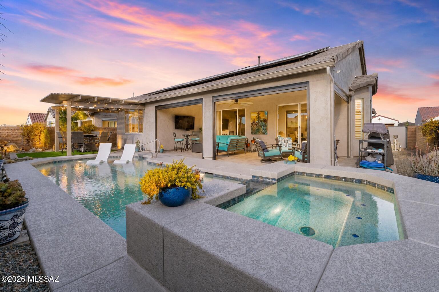 Meticulously upgraded with approximately $188,000 in upscale finishes, this exceptional residence is perfectly positioned on a premium corner lot capturing sweeping views of Mt. Wrightson, Mt. Hopkins, Madera Canyon, and Josephine Saddle from the backyard. Located within the prestigious gated 55+ community of Quail Creek, this impeccably maintained 2021-built home reflects refined design, thoughtful investment, and true pride of ownership. Offering 2 bedrooms, 2.5 bathrooms, a private den, and 1,744 sq ft, the home seamlessly blends luxury and comfort. A fully paid 30-panel owned solar system provides outstanding energy efficiency, with average electric bills of approximately $45 per month. Interior finishes include plank ceramic tile throughout the main living areas, plush carpeting in the bedrooms, plantation shutters, and ceiling fans in every room. The great room is anchored by a dramatic 78" electric fireplace framed by a custom tiled feature wall, creating an elegant modern focal point. The den is enhanced with a custom sliding barn door, adding warmth and character. Designed for both entertaining and everyday living, the gourmet kitchen showcases quartz countertops, a curved granite island, upgraded 41" cabinetry with crown molding, stainless steel appliances, under-cabinet lighting, and designer pendant accents.
Outdoor living is elevated to a resort-style experience featuring a heated PebbleTec saltwater pool and spa, retractable solar screens with wind sensors, a pergola positioned to capture breathtaking Santa Rita Mountain views, a tranquil water feature, and professionally designed desert landscaping highlighted by a mature saguaro cactus.
Additional amenities include an extended-length two-car garage plus a golf cart garage, built-in storage cabinetry, whole-house water conditioning, a custom mahogany front entry door, and a powder-coated wrought-iron security entry. An integrated audio/video system is also available with a seller-acceptable offer.
This remarkable home offers an extraordinary combination of luxury, energy efficiency, and lifestyle within one of Quail Creek's most sought-after settings.