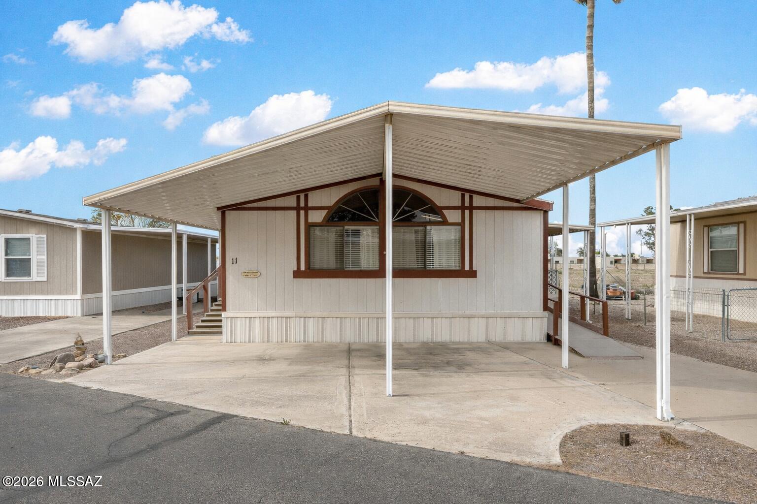 This 2-bed, 2-bath MH in Valley of the Sun Mobile Home Park offers a comfortable layout with inviting indoor and outdoor living spaces. A covered 2 car carport provides shaded parking, while the front entry opens to a spacious living room with large arched windows that bring in natural light. The living area flows into a dining space and kitchen featuring ample cabinetry, and generous counter space. The primary bedroom includes a large closet and private bath, while the second bedroom is located near a full guest bathroom. A dedicated laundry room offers additional storage and convenient access to the covered patio, creating an easy transition to outdoor relaxation. Fenced in Yard perfect for any pet. Location is close to Rec Room, Pool, Amenities and Mailboxes. Land lease is 634 amont