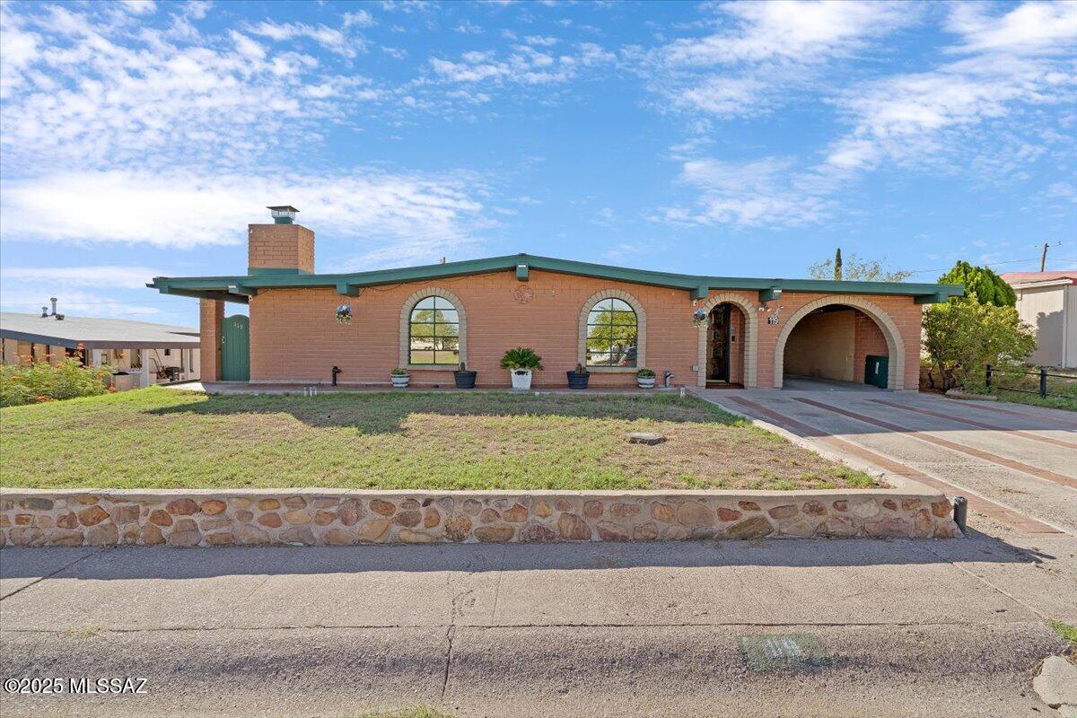 Step into timeless character and craftsmanship with this one-of-a-kind, 3 bedroom 1 bath, 1962 slump block bungalow in historic San Manuel. Lovingly cared for by only 2 owners, this 1,825 sq. ft. home showcases true vintage charm with vaulted ceilings, exposed wood beams, and a stunning brick fireplace that anchors the spacious living room. From the moment you step inside, you'll feel home. The custom brick and stone tile finishes, built-in bookshelves in entry & dining areas, and beautiful French wood doors that bring in soft natural light create a timeless cozy rustic atmosphere. The kitchen is adorned with a custom-built brick breakfast bar (unique iron Arizonian stools included), Being sold  AS IS'' Knotty pine handmade cabinet fronts & built-ins that add warmth and personality you won't find in newer homes. While modern touches like the Kenmore Elite refrigerator & GE convection oven give you peace of mind.
The spacious primary bedroom is truly a retreat! Measuring 20' x 15', with vaulted wood-planked ceilings, an impressively large 17-foot mirrored walk-in closet, and private outdoor access. Every detail speaks to quality and durability, from the masonry construction to the thoughtful built-ins that maximize both beauty and function. A second bedroom and cozy 13' x 10' Arizona room provide extra space, opportunity, and flexibility to have for an office, sunroom, gameroom, or studio. 
The bathroom is generously sized and beautifully tiled from floor to ceiling! Soak away the worries of the day in the spa tub, with tiled step decking, surrounded by your favorite candles, salts, and plants. OR step into your tiled walk-in shower with the option to control water usage with a water-saving toilet and classic pedestal sink past and present blend seamlessly even here.
Outdoors, the back and side yards are enclosed by a masonry wall and 2 sets of double gates giving you true privacy, access, and peace of mind. Car enthusiasts, those who love to tinker or those needing serious workshop space, will truly appreciate the detached 2-car garage. It measures 16' x 30' & includes hookups for an air compressor, arc welder, and more. Entertainers will enjoy the shaded carport area that extends from the garage, the brick garden boxes ready for flowers or vegetables, mountain views and the built-in masonry BBQ. 
This home offers the perfect blend of privacy, comfort, character, community and utility. Conveniently located the community center, playground, public school, library, and local shops are all within walking distance and Highway 77 offers an easy 30-40 minute commute into Catalina and Oro Valley. This gem is worth seeing in person!