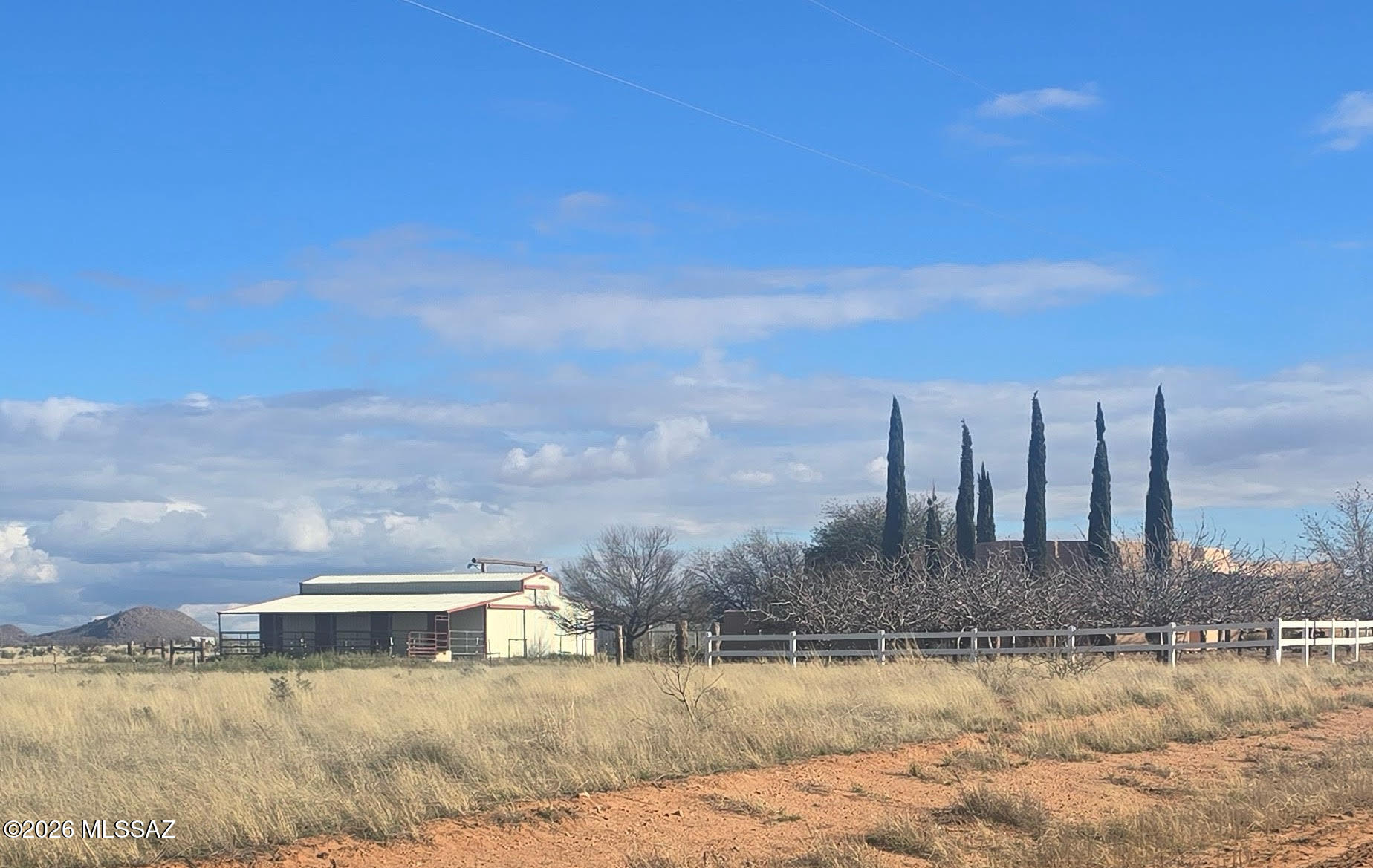 Country living at its finest, with sweeping views of the Dragoon Mtns &  Cochise Stronghold. This custom Santa Fe home rests on 3.3 acres and offers 2,384 sq ft with 3 bdrms & 2.5 baths. A welcoming Great Room opens from the foyer and kitchen, creating an easy, open flow. The kitchen features custom tile, granite counters, and oak cabinetry, while the formal dining room is accented by beautiful hardwood floors.
The spacious master suite provides a quiet retreat with a gas log fireplace, oversized walk-in shower, custom closet, & direct access to the deep covered patio & chainlink-fenced backyard. 
The property is well-equipped for animals and hobbies, offering a 48x36 enclosed barn with shop & 1/2 bth plus 2 fenced pastures, greenhouse, & small pistachio orchard complete this Rural setti