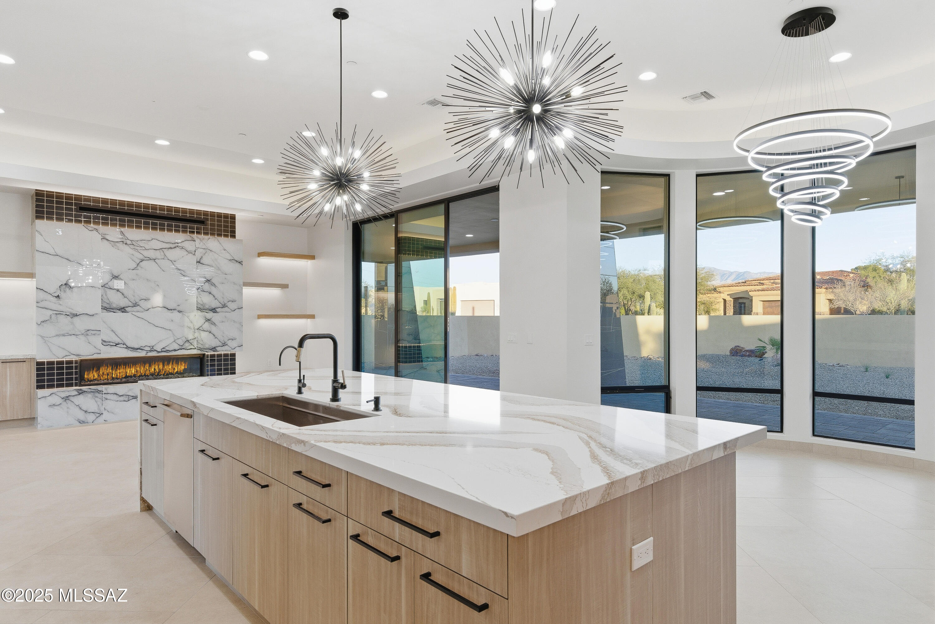 Welcome to 11961 N. Mesquite Sunset Place -- a stunning, move-in ready new construction custom home built by Homes by Copper Canyon in Oro Valley's prestigious gated community of Sunset Canyon Estates. Set on a generous .84-acre estate lot with panoramic mountain views, this single-story contemporary masterpiece delivers the finest in Sonoran Desert living.
Inside the 2,566 square feet of thoughtfully designed space, you'll find 3 bedrooms, each with its own ensuite bath, plus a powder room -- a rare and elegant touch. The primary suite is a true retreat, featuring an oversized soaking tub and shower framed by a dramatic wall of glass. Seven skylights bathe the home in natural light, while a cozy fireplace creates an inviting anchor for the living space. The chef's kitchen is appointed with Stainless Electrolux appliances, a Next Gen induction cooktop, European-style full-overlay cabinetry with custom stain finish, and a striking Cambria Britannica Gold waterfall-edge quartz island. A walk-in pantry, reverse osmosis and soft water system, and morning room complete this exceptional kitchen experience.
Additional highlights include oversized tile floors throughout, high ceilings, no interior steps, a covered patio, and an oversized 3-car garage with paver driveway and turnaround. Smart thermostat, pre-wired security, round out the package.
Located minutes from shopping, dining, and medical services, and within walking distance of highly-rated Wilson K-8 -- this turnkey home is ready for you today.