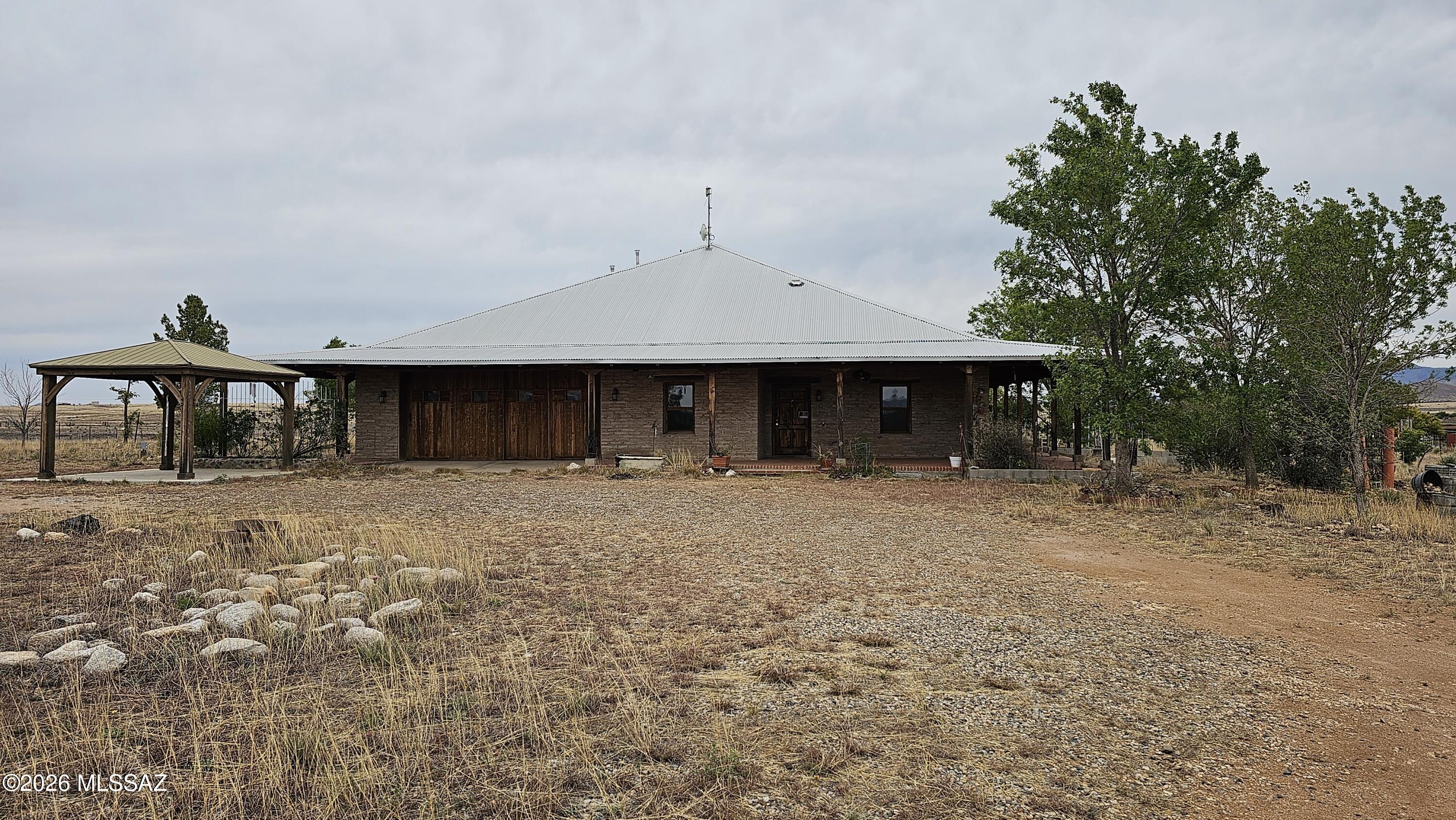Situated on 4.9 acres in Elgin's Wine Country with beautiful mountain views, this property offers space, character, and privacy. The home features four bedrooms, two bathrooms, plus a separate study/office and a two car garage.

Designed with distinctive Southwest craftsmanship, the house includes 10ft high, 25in thick adobe walls, a durable steel roof, pine wood flooring, redwood doors and cabinets, and mesquite kitchen countertops. Wraparound covered porches provide the perfect place to relax and enjoy the surrounding field and mountain vistas visible from nearly every window.

Recent Appraisal indicates value of $665,000. Comfort features include luxurious under floor radiant heat throughout the home. The bathrooms include jetted tubs and a dual head steam shower. The chef's kitchen is equipped with a professional Thermador stove and refrigerator, offering both style and performance.

A unique property with acreage, views, and quality construction in the heart of Elgin's Wine Country.