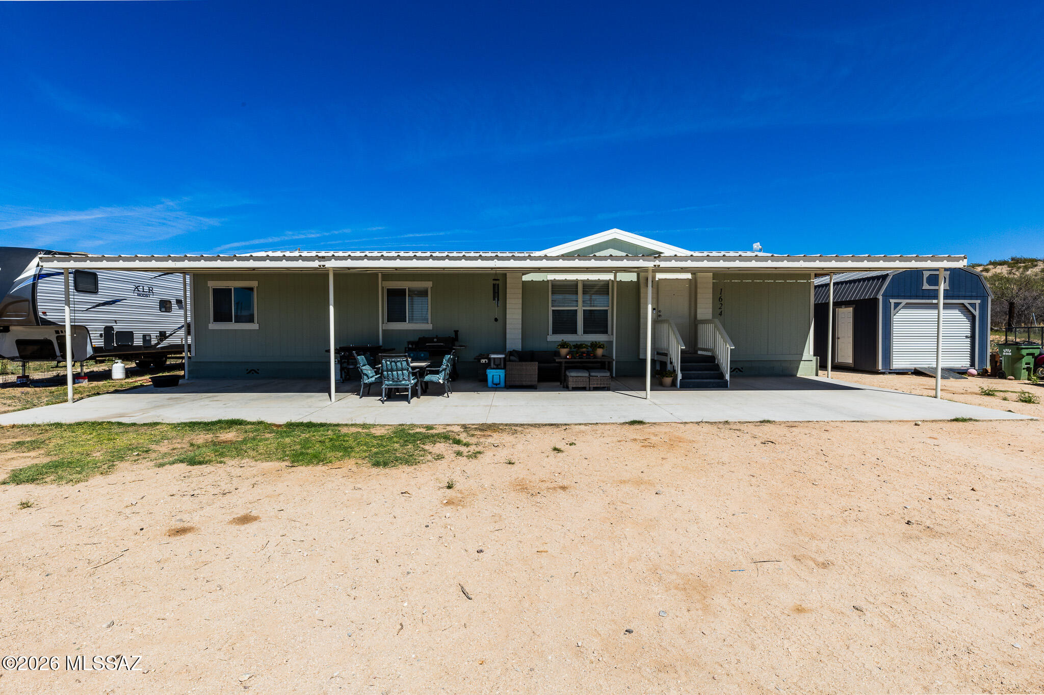 Welcome to this cozy manufactured home featuring open living room, 3 bedroom 2 bathrooms on just over 1.5 acres of peaceful desert landscaping. Inside you will find attractive laminate flooring and stylish kitchen with stainless steel appliance that add a sleek, modern touch. Step outside to a covered patio ideal for enjoying the Arizona sunsets, while the partially fenced lot provides space for animals, hobbies or outdoor activities. With expansive desert views and a shared well, this property offers the perfect blend of comfort and country living. RV space available with electric hook ups and septic connection. Shed does not convey with the property and will be moved prior to closing.