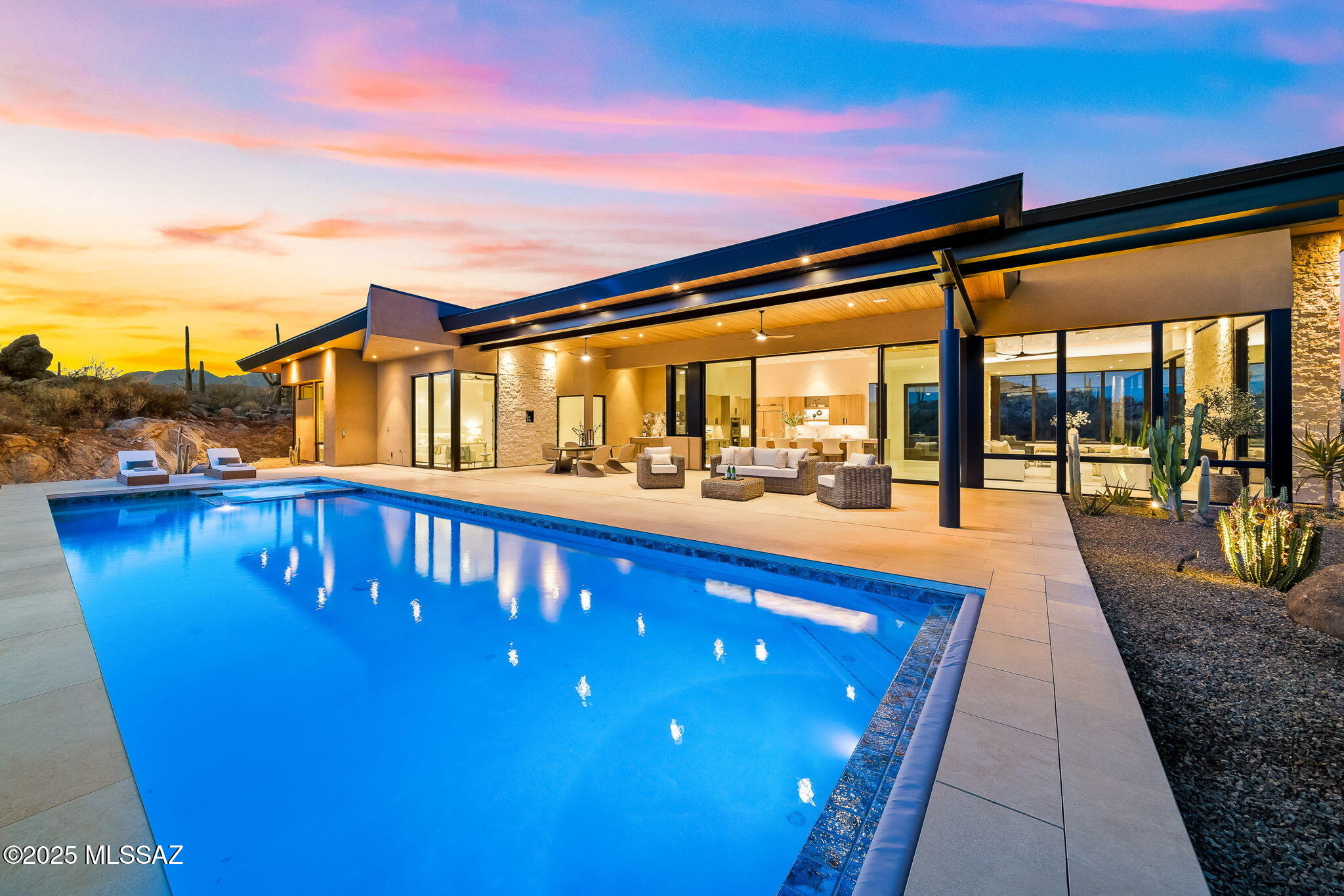 Completed in 2025, this refined estate is set on 1.65 acres in the coveted guard-gated community of Stone Canyon- Oro Valley's most esteemed luxury community. To further enhance the lifestyle experience, the seller is offering an incentive to cover the $25,000 Stone Canyon Club Membership initiation fee. This striking residence by Soloway Designs is a true architectural statement, artfully blending contemporary elegance with the serenity of the Sonoran Desert.
Spanning 3,792 sq ft, the home offers 3 spacious bedrooms, 4 bathrooms and a 3-car garage, all crafted with exceptional attention to detail.   Expansive floor to ceiling  windows capture gorgeous, wide views of the Catalina Mountains, infusing the interiors with natural light and uninterrupted desert beauty.
The designer kitchen is as functional as it is refined, outfitted with top-of-the-line Wolf and Sub-Zero appliances, a large center island with seating and a generous pantry for seamless entertaining.  
Natural stone surfaces, custom cabinetry, and tongue and groove ceilings create a harmonious blend of luxury and comfort.
Expansive 10-foot sliders open effortlessly to a magnificent outdoor patio, with lap pool/ spa providing a secluded sanctuary, an idyllic setting to savor the breathtaking views of the rugged rock formation, dramatic boulders, and iconic saguaros. Whether hosting an intimate gathering or enjoying a quiet moment, the outdoor living spaces are designed to impress.  
The luxurious primary suite is a tranquil retreat with panoramic desert views.  The bath is a sanctuary in itself featuring a steam shower, radiant heated flooring, and a relaxing soaking tub.  The expansive custom closet includes built-in storage and a quartzite island, ensuring a seamless blend of style and functionality.
An adjacent flex room provides versatile space perfect for an exercise room, home office, or den, complemented by a screened-in patio that beckons you to enjoy the fresh desert air.  
Spacious guest bedrooms, beautifully appointed to capture views of the Catalina Mountains, each with their own ensuite. Electronic blinds, a whole-house Sonos system, a security system, and TV's are all included, making it effortless to move right in and start enjoying the home from day one. A three-car garage with an extra storage room completes this extraordinary offering.
As a resident of the Stone Canyon Club, you will enjoy a wealth of amenities, including an elegant clubhouse with a restaurant, state-of-the-art fitness center, lap pool, hot tub, tennis, pickleball and a vibrant calendar of social events.  Located just minutes from hiking and biking trails, exquisite restaurants, premier shopping, and world-class healthcare, this home encapsulates the very essence of luxurious, convenient living.
