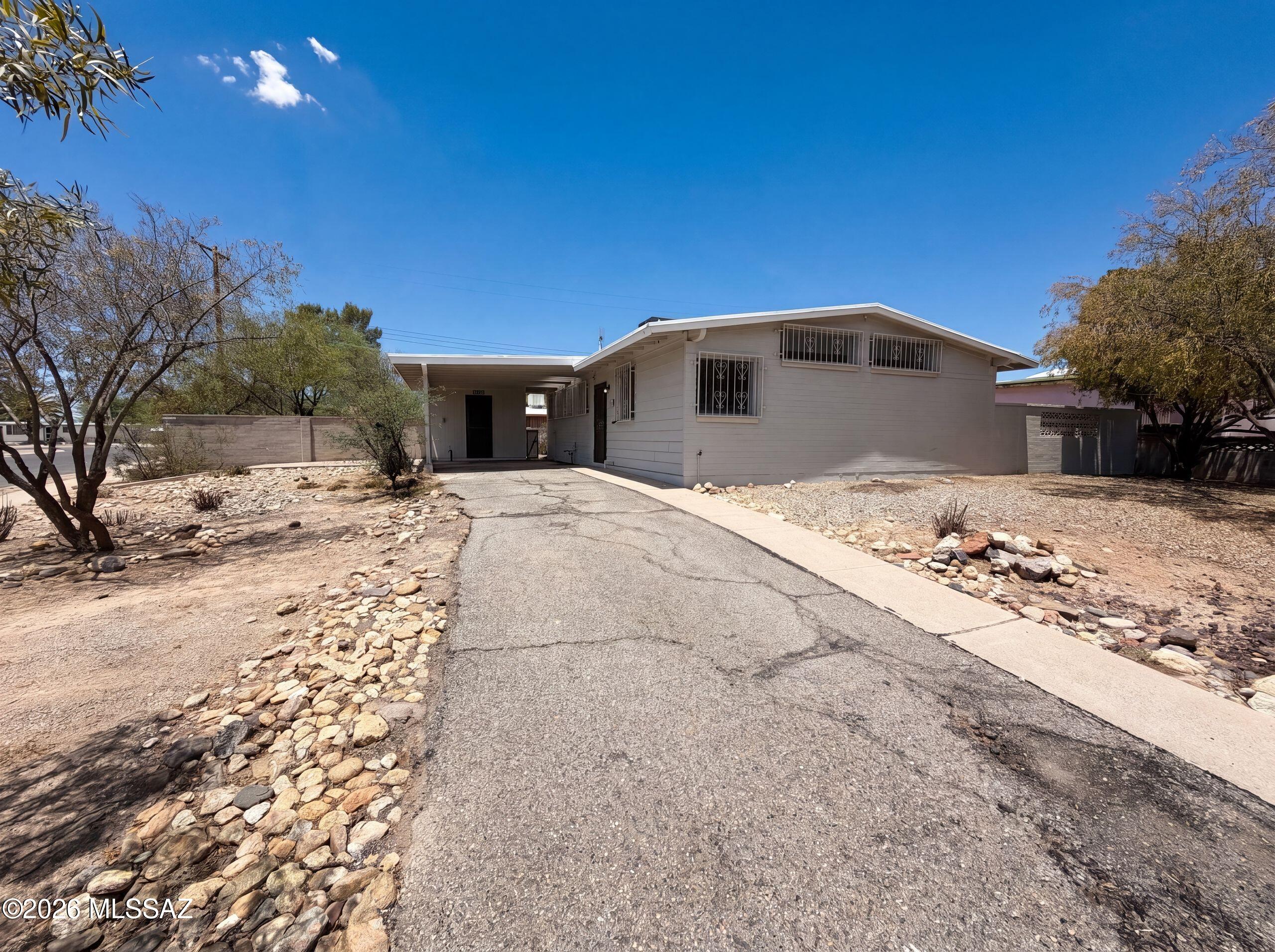 2901 N Cloverland Ave is a 1-story Tucson single-family home built in 1960, offering 3 bedrooms and 2 bathrooms across 1,223 square feet. The kitchen features oak cabinetry, granite countertops, and stainless steel appliances including a gas range. The living areas connect through the home with hardwood-style flooring, and the bedrooms include carpet. Two full bathrooms serve the home, one with a tub/shower combination and one with a walk-in shower with tile surround. The large desert yard with mature trees provides outdoor space, and multiple exterior angles highlight the home's curb appeal across the surrounding neighborhood.. Included 100-Day Home Warranty with buyer activation