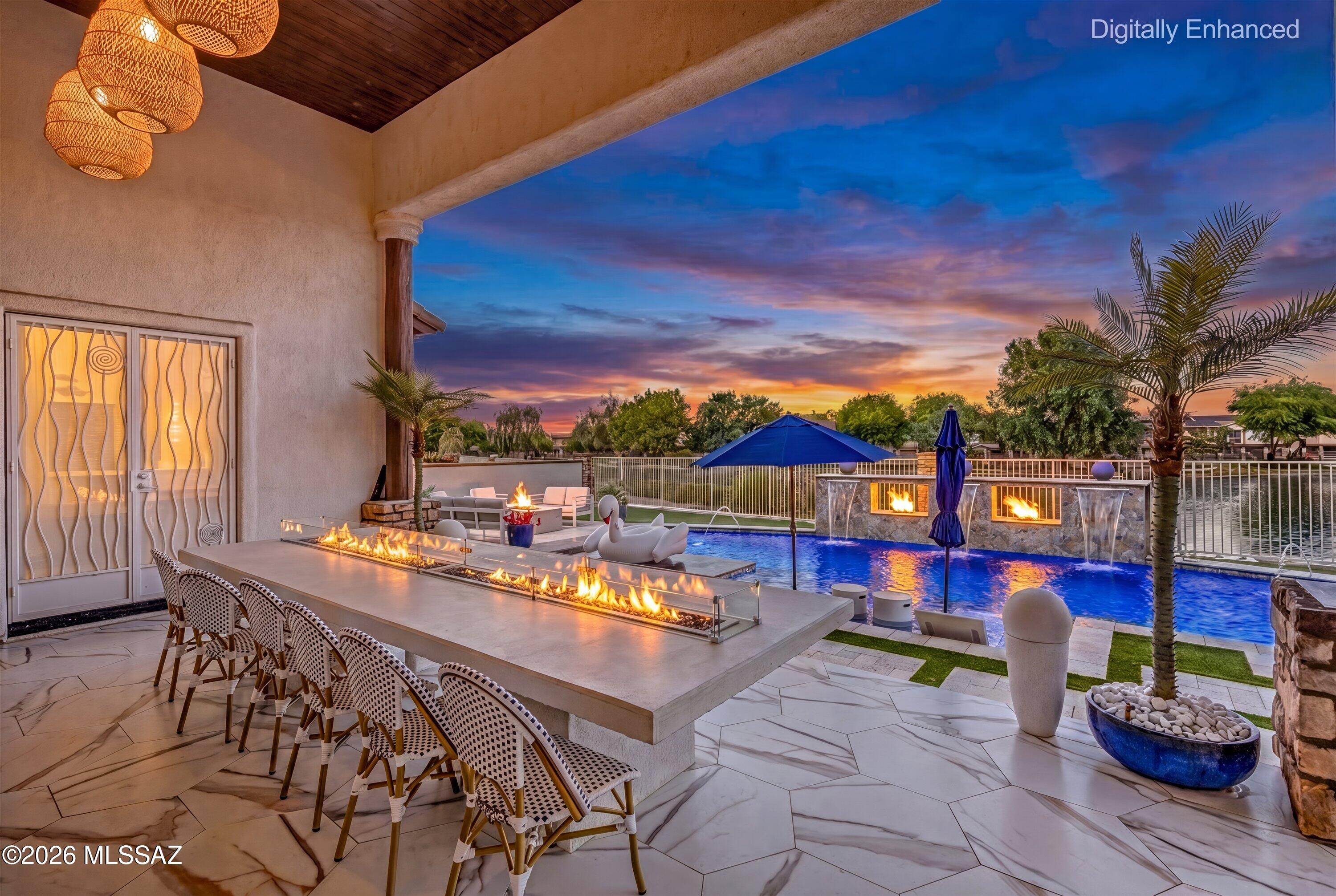 Welcome to one of Rancho Sahuarita's most extraordinary offerings, a rare opportunity within an exclusive gated enclave of just 18 homes. Perfectly positioned near the community clubhouse and overlooking the sparkling waters of Sahuarita Lake, this remarkable single-story estate offers a level of luxury, privacy, and lifestyle that is seldom available and nearly impossible to replicate.
From the moment you arrive, the home's presence is undeniable. A long paved driveway creates a grand approach, leading to an impressive four-car garage and an expansive gated side yard designed to accommodate boats, trailers, oversized vehicles, and all the toys that accompany an active Arizona lifestyle. A charming front courtyard welcomes you inside, setting the tone for the elegance and thoughtful design that awaits beyond.
Every detail of this home has been carefully curated to create an elevated living experience. Light-filled interiors showcase stunning porcelain tile flooring, dramatic designer lighting, and a striking custom tile feature wall that serves as a true statement piece. Expansive picture windows frame breathtaking lake and mountain views while filling the home with natural light. At the center of the home, the stunning chef's kitchen is a true showpiece, featuring elegant marble countertops and backsplash, a premium suite of ZLINE luxury appliances, and designer finishes throughout. Equal parts beautiful and functional, this space was designed to impress--from intimate family dinners to large-scale entertaining, while offering the performance and craftsmanship discerning buyers expect.
The thoughtfully designed floorplan offers space and flexibility for every stage of life, including a private office, versatile den, guest suite with its own ensuite bathroom, two secondary bedrooms connected by a Jack-and-Jill bathroom, and a spectacular primary retreat. Wake each morning to serene lake views and unwind in a spa-inspired bathroom designed to feel like a private resort. The primary suite is a true sanctuary, offering the perfect blend of comfort, luxury, and tranquility.
While the interior is stunning, it is the resort-style backyard oasis that truly transforms this property into something extraordinary. Designed to rival a luxury retreat, this spectacular outdoor living space offers breathtaking lake and mountain views, a heated PebbleTec pool, oversized spa, swim-up bar, sunken outdoor kitchen, multiple fire features, and unforgettable spaces to gather, entertain, and relax. A custom concrete dining table with an integrated fire feature creates a striking focal point, while the expansive covered patio, dramatic picture windows, and stunning see-through fireplace seamlessly blend indoor and outdoor living.
As the sun sets, the backyard oasis comes alive with glowing fire features, illuminated water elements, and shimmering reflections dancing across the lake. It's the kind of setting most people dream about while planning their next getaway--except here, it's yours to enjoy every single day. Every day feels like a vacation when you're living here because the resort experience is quite literally in your own backyard. Whether hosting unforgettable gatherings, enjoying quiet evenings under the Arizona sky, or spending weekends poolside with family and friends, this outdoor environment was designed to create lasting memories.
Beyond the beauty and luxury, the location is simply exceptional. Enjoy close proximity to Rancho Sahuarita's award-winning amenities, including the clubhouse, lake, parks, walking trails, pools, splash park, fitness facilities, and community events that make this one of Southern Arizona's most sought-after master-planned communities. Fruit trees, spectacular mountain views, and the rare combination of privacy, space, and convenience further elevate this one-of-a-kind property.
Opportunities like this are exceptionally rare. Combining an irreplaceable lakefront setting, breathtaking mountain views, premium ZLINE appliances, designer finishes, expansive RV and toy storage, and a truly exceptional resort-style backyard oasis, this remarkable property represents one of the most exclusive opportunities to become available in Rancho Sahuarita. Every day feels like a vacation, where sunsets over the lake, evenings by the fire, and unforgettable gatherings become part of everyday life. More than a home, it is a destination, an extraordinary place to gather, celebrate, relax, and create memories for years to come