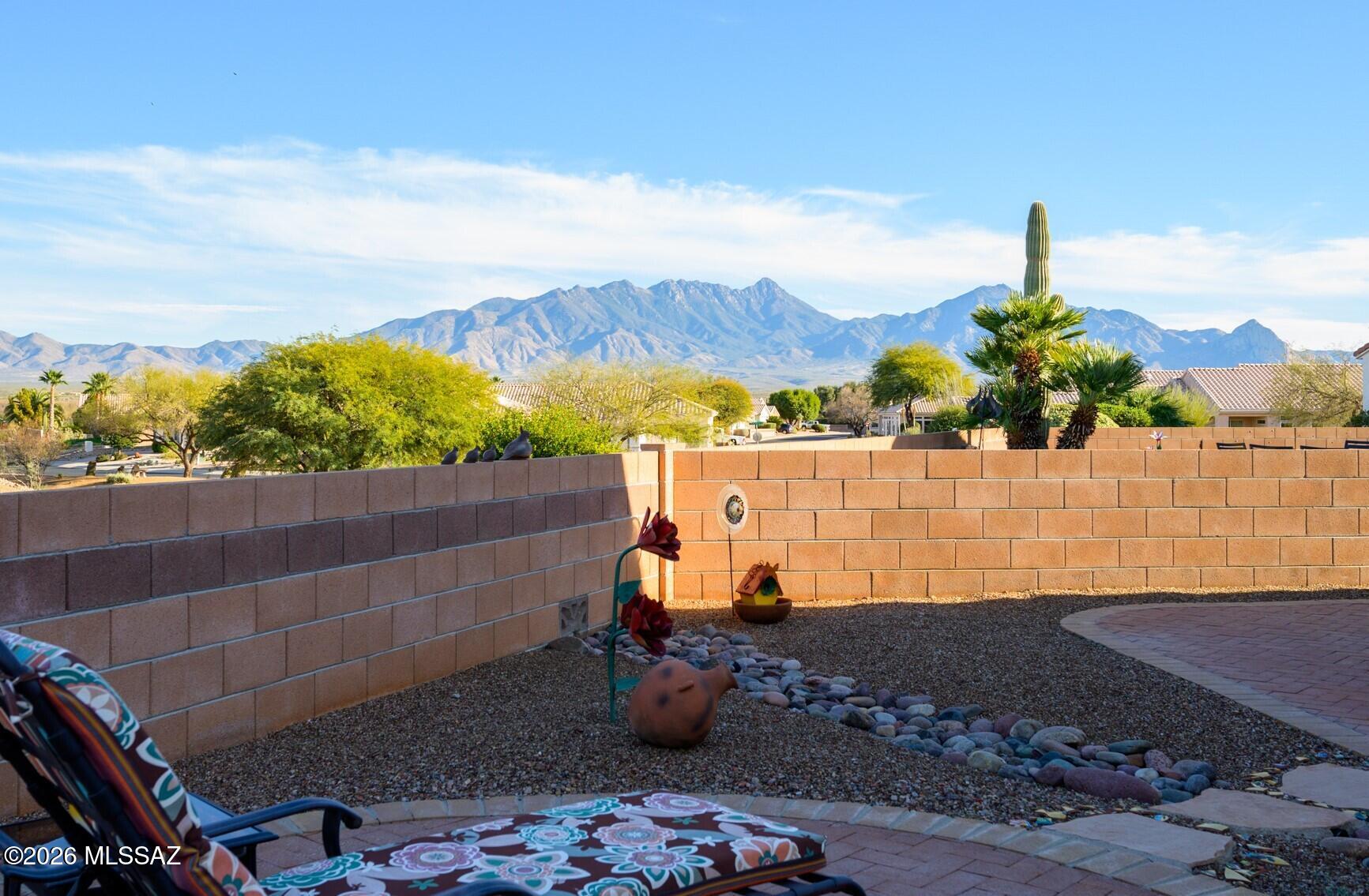 A stately saguaro and a classic southwest slump block wall set the tone for the warm desert charm that defines this home. Move inside to a bright, cheerful great room where oversized offset tile, corner view windows, and sliding glass doors flood the space with natural light and frame the surrounding desert scenery.   The eat-in kitchen nook is wrapped in sunshine thanks to a large plate glass window and an additional slider that opens to the patio with great mountain views.  The kitchen itself shines with artistic polished countertops, white appliances, and a glass cooktop range — the perfect blend of style and practicality.  Your spacious owner's suite continues the theme of light and views, offering a peaceful retreat and an ensuite bath with dual vanities and a dedicated makeup station.  Car enthusiasts and hobbyists will love the oversized 2-car garage featuring epoxy concrete floors, workshop-grade fluorescent lighting, and garage door windows that fill the space with natural light.  Outdoor living is effortless here.   Enjoy open-air dining or quiet mornings on the tiled, covered patio overlooking serene desert vistas.  The low-maintenance landscaping means more time to relax and soak in the Southwest lifestyle. This home blends charm, comfort, and functionality  properties with this combination of views, light, and thoughtful upgrades don't come along often.  Come see why this one stands out.
