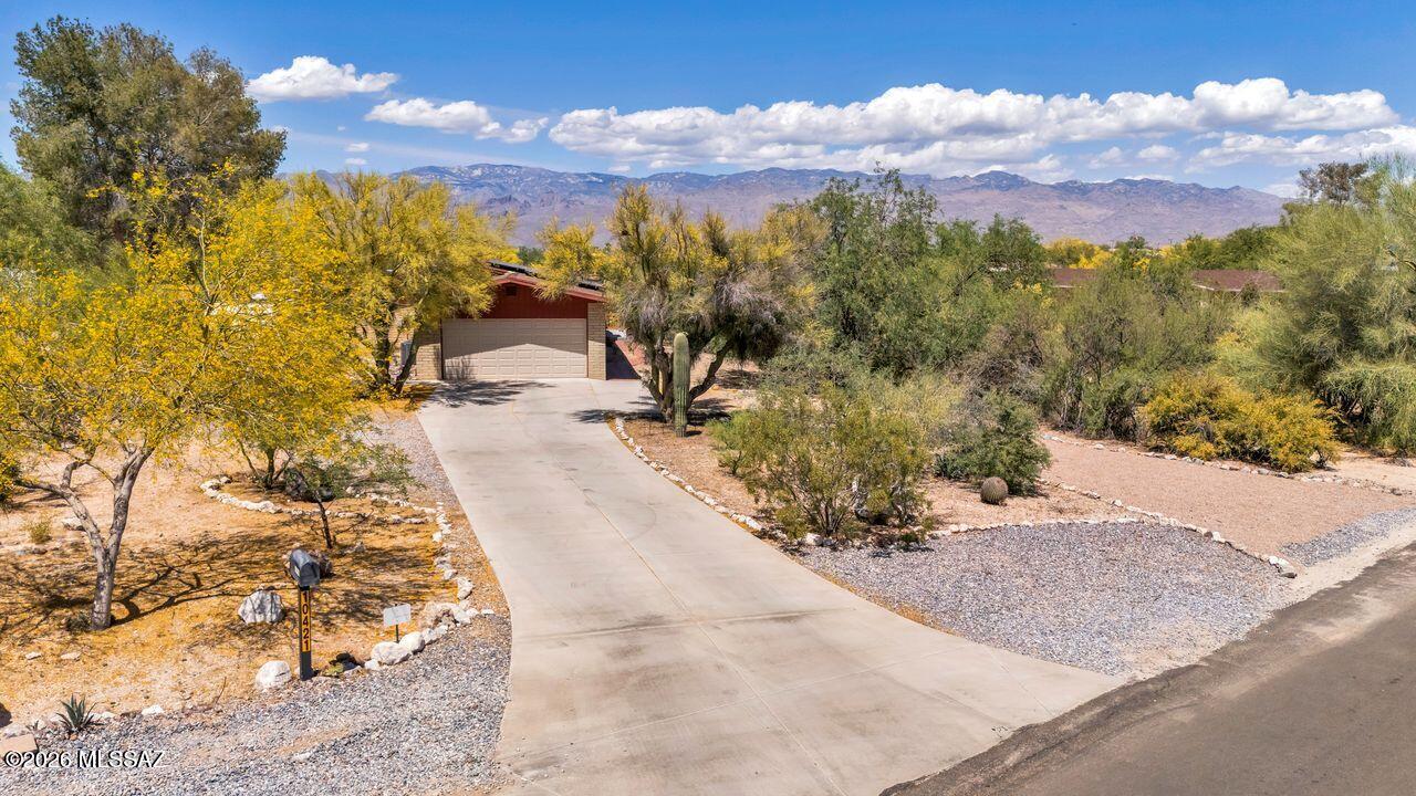 Got Toys? Enjoy peaceful outdoor living from the raised front deck with beautiful mountain views overlooking the wash, desert vegetation, and local wildlife. This amazing ranch-style home features tile floors throughout and dual-pane windows for comfort and efficiency. With no HOA and a just-under-one-acre lot, there's ample parking, with a 2nd driveway--including room for your RV. The spacious yard offers room for gardening (with a fenced raised-bed area), horseshoes, and plenty of space to relax or entertain, all shaded by mature trees. Inside, the library showcases floor-to-ceiling custom bookcases, while the living room features a cozy wood-burning fireplace. An extra-deep 2-car garage and a paid-off solar lease with 5 years remaining add even more value.