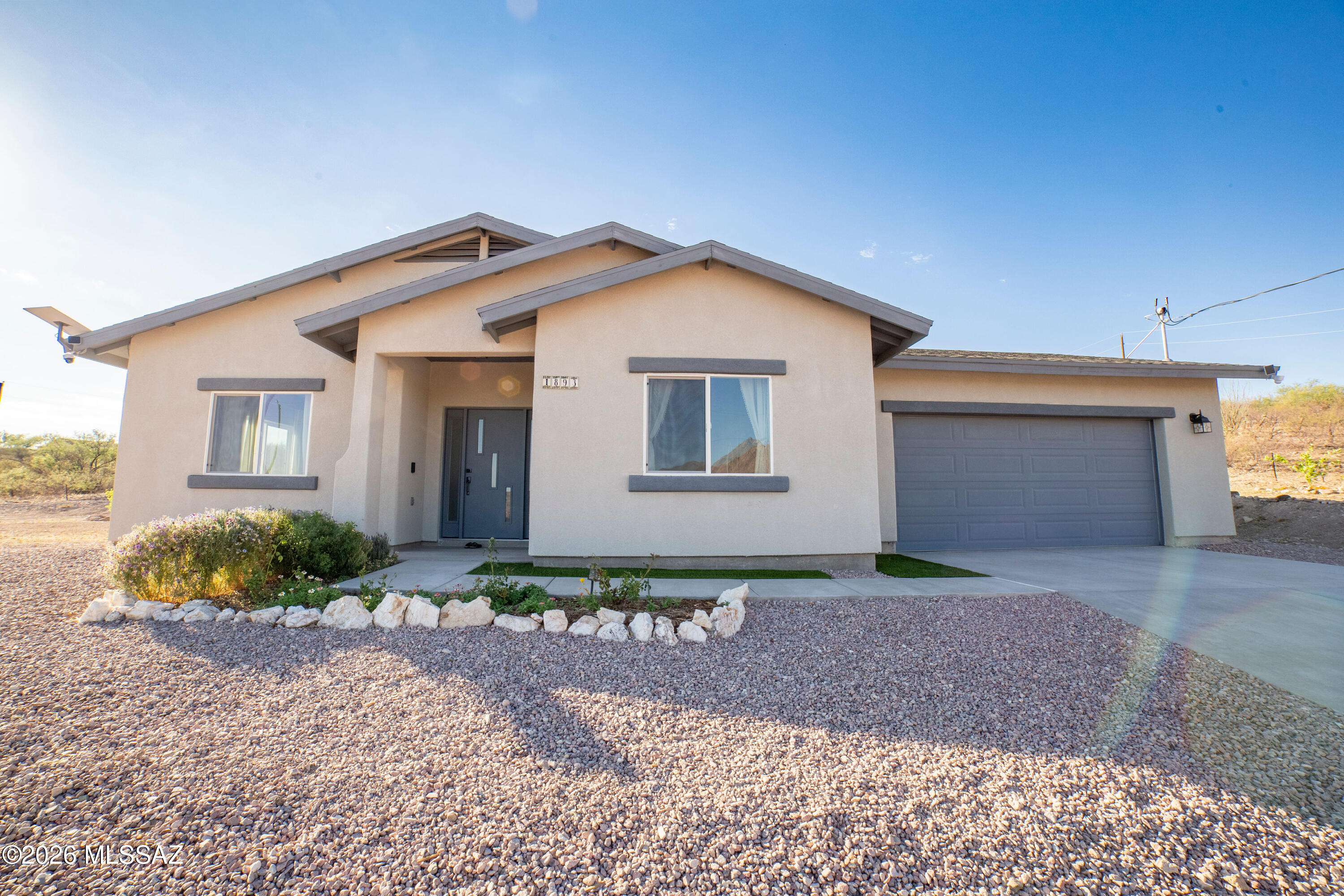 This beautiful new home welcomes you with stunning views of the Tumacacori Mountains and a bright, open layout designed for comfortable everyday living and easy entertaining. As you enter, the living room sits to the left, while the kitchen and dining area are thoughtfully positioned to the right, creating a warm and inviting flow through the main living space. Large windows throughout the home bring in natural light and showcase the mountain views from multiple rooms. The bedrooms are tucked down the hall, offering separation between the hosting areas and private living quarters. The garage features epoxy flooring, adding a clean and functional finish, with plenty of space for storage or hobbies. Additional features include security cameras, a water softener, and reverse osmosis system. Outside, enjoy a variety of fruit trees including apricot, apple, lemon, and two orange trees, along with mature ash and pine trees. Workout equipment may be available for purchase on a separate bill of sale.