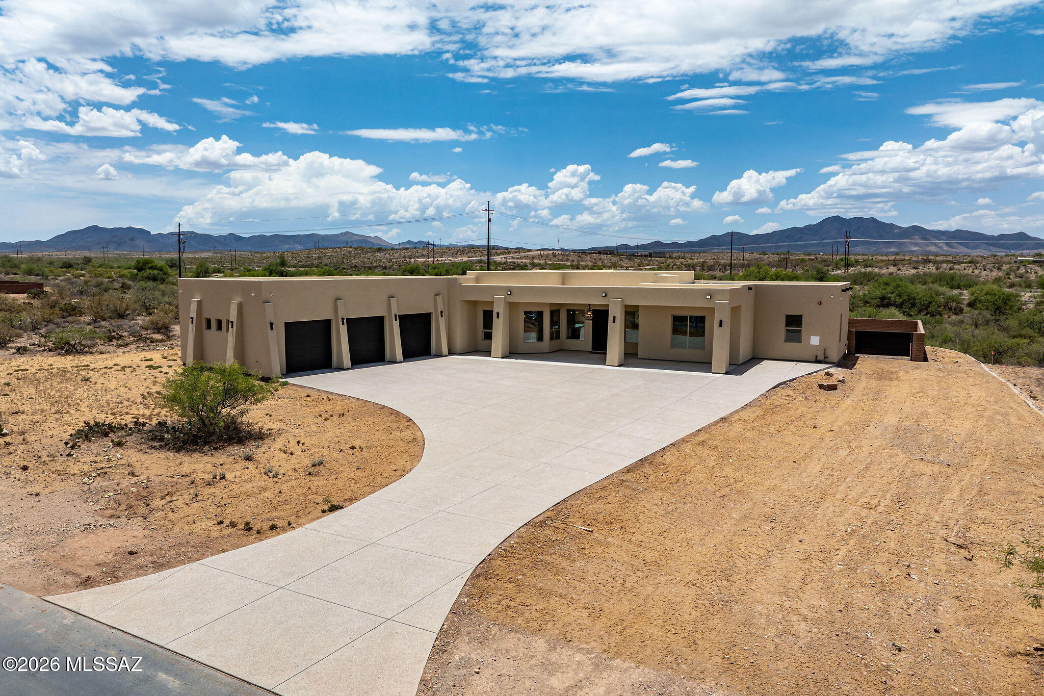 Custom-built slump block home situated on a sprawling 1.31-acre lot with an impressive 5,181 square feet under roof, including expansive patio and an extended 3-car garage. The oversized aggregate driveway provides parking for 10+ vehicles, making this property ideal for entertaining, while the large enclosed backyard features a block wall, double gate access, RV parking, and plenty of room to add a pool, workshop, or additional recreational amenities.
Designed with modern living in mind, this exceptional home offers 4 bedrooms, 3 bathrooms, plus a versatile bonus room off the primary suite that is perfect for a home office, gym, nursery, or private retreat. Soaring 12-foot ceilings highlight the main living areas, while 10-foot ceilings throughout the remainder of the home create create a spacious and open atmosphere. A stunning 12-foot sliding glass door seamlessly connects the indoor and outdoor living spaces, opening to an extended wraparound covered patio designed to take advantage of year-round shade and Arizona's beautiful weather.
The gourmet kitchen is the centerpiece of the home, featuring a spectacular 9-foot waterfall quartz island with seating for six, pendant lighting, and additional storage beneath. Custom cabinetry with elegant gold hardware, a stainless-steel farmhouse sink, modern fixtures, oversized walk-in pantry, and premium stainless steel appliances complete the space. Appliances include a gas cooktop on double ovens, decorative hood, French door refrigerator, built-in microwave, and dishwasher. 
The luxurious primary suite is truly a showcase, offering a spa-inspired bathroom with a dramatic walk-through shower featuring a stone accent wall, dual quartz vanities, pendant lighting, framed mirrors, makeup station, soaking tub with handheld faucet, and an oversized walk-in closet complete with custom built-in shelving. The secondary guest suite enjoys its own private bathroom featuring a floating vanity, quartz countertops, undermount sink, custom mirror, modern lighting, and a floor-to-ceiling tiled shower with glass enclosure.
Additional upgrades include beautiful large tile flooring, modern ceiling fans throughout, foam insulation for energy efficiency, security camera system, oversized laundry room with sink, overhead cabinetry, and both gas and electric dryer hookups. The extended 3-car garage features 11-foot ceilings and 8-foot garage doors, providing ample room for trucks, boats, recreational vehicles, toys, and a workshop. This one-of-a-kind property combines luxury finishes, energy efficiency, abundant storage, and exceptional indoor-outdoor living on a premium acreage homesite. In comparison of other homes in the area, this home has far more custom features and upgrades.  Come see the difference.