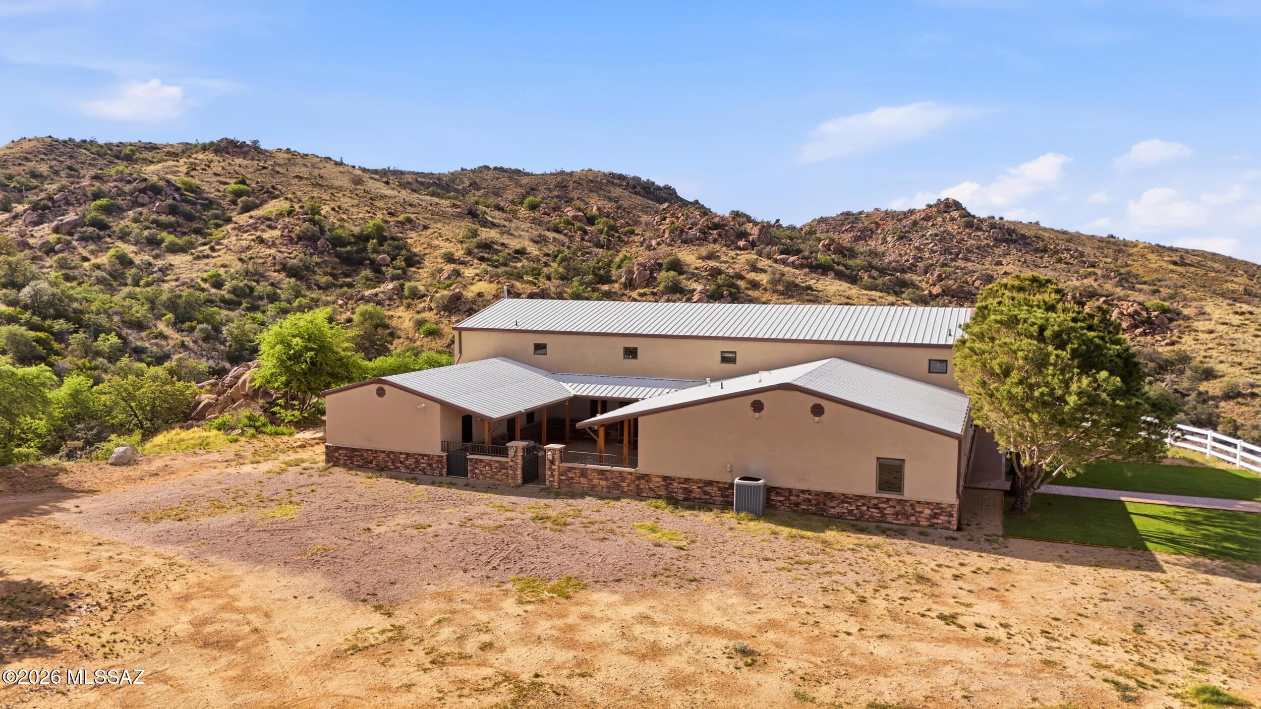 Seller shall consider and/or counter offers within a range of $1,187,500 to $1,250,000. Welcome home to Hilltop Luxury with Panoramic Views & Endless Possibilities. Custom-built estate on 7 private acres surrounded by Coronado National Forest with mature trees & direct Arizona Trail access. Primarily single-level living with loft above. Light-filled interior with vaulted wood ceilings, spacious kitchen with breakfast bar & dining area, plus entertainer's lounge with built-in bar, drop-down movie screen, & pool table area. Arizona Room with built-in BBQ opens to patios & scenic platforms perfect for gatherings. Main home offers 3 bonus rooms, highlighted by a metal roof & natural rock. No HOA-bring your toys and RVs with full hookups. Includes a permitted 5,000 sq ft climate-controlled garage/barn with two RV doors, half bath, office, laundry, & a bonus suite with adjacent kitchen & bathroom. Plus permitted 720 sq ft horse facility with stalls, turnouts, & tack room. An ideal season retreat with space for RV's, equipment, or equestrian us - perfect for those seeing a mild winter escape and year-round outdoor living. Imagine the memories you'll make here!