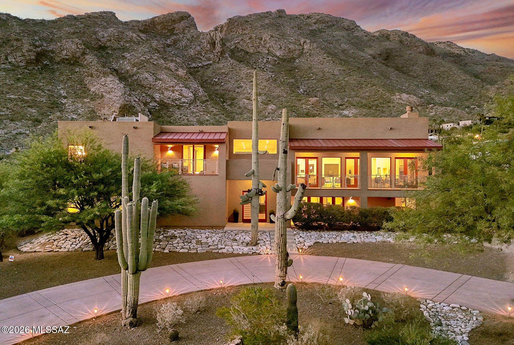 Exceptional Coronado Foothills Estates, 6321 sq ft, contemporary residence with sweeping city lights and stunning mountain views. Originally built in the 1970s, this home was extensively rebuilt from the ground up, resulting in an effective age of 2003. Impressive foyer entry with 20' + ceilings and dramatic staircase open to a spectacular great room with 10' ceilings, expansive windows, fireplace, French doors, and spacious dining area designed for entertaining. The Cook's kitchen is beautifully appointed with granite countertops, stainless steel appliances, and custom finishes. Rich wood flooring and stone tile accents add warmth and elegance throughout the home.
Offering 4 bedrooms split floor plan, plus downstairs, a media room and separate game/recreation room, this home provides both comfort and flexibility. The expansive primary suite features a private sitting area, luxurious spa-style bath, generous walk-in closet, and private balcony overlooking the incredible views. Resort-style backyard includes a covered patio, Santa Catalina mountain vistas. Additional highlights include a 4-car garage, with tons of off street parking, on a .89 acre lot.