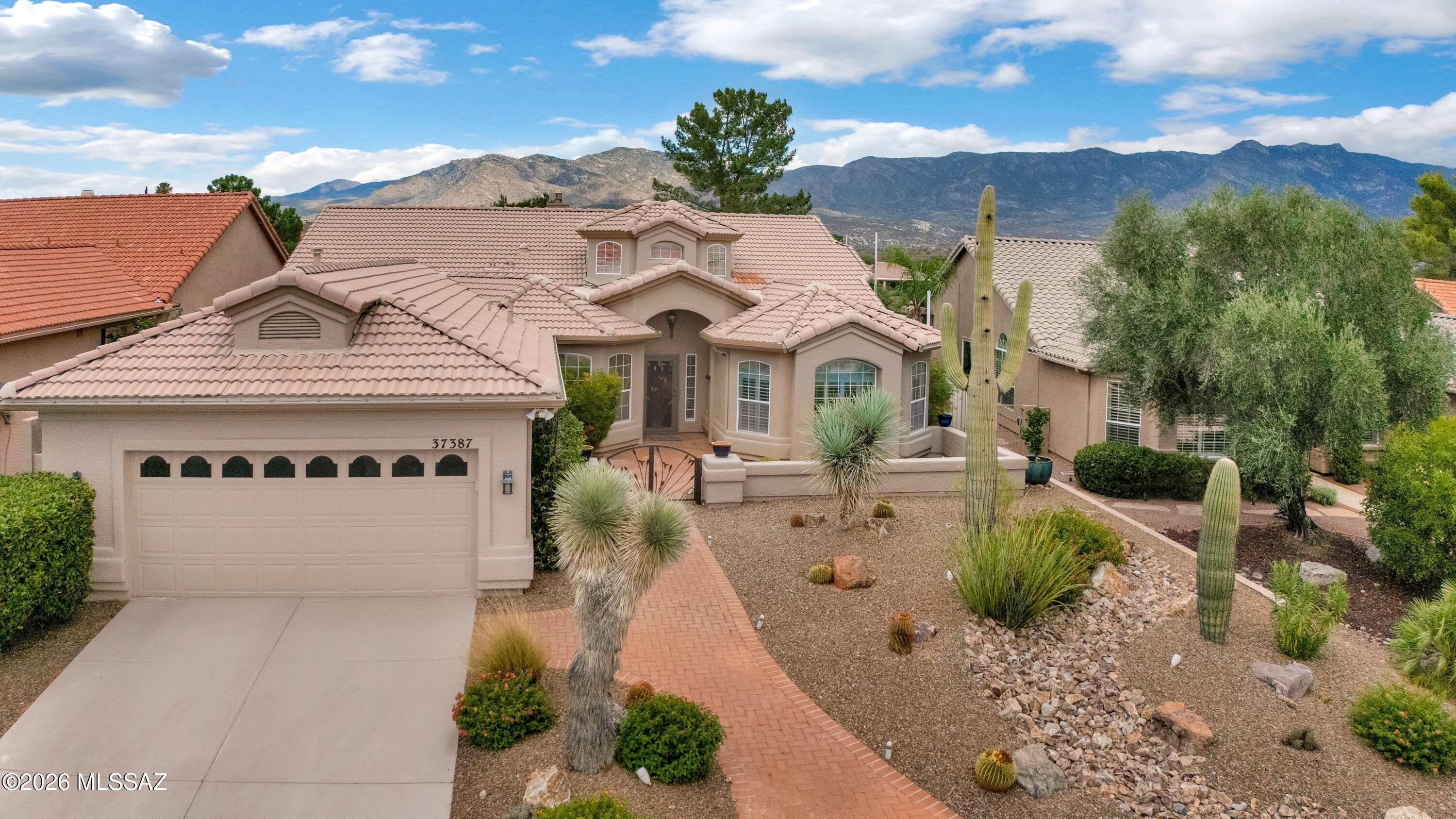 Experience the best of SaddleBrooke living in this east-facing 3-bedroom, 2-bath Cambria overlooking the golf course with breathtaking panoramic lake and mountain views. A welcoming courtyard leads to an open floor plan with vaulted ceilings, plantation shutters, electric shades, stainless steel appliances, and a family room featuring a gas fireplace and granite walk-in bar. Spacious living and dining rooms are ideal for entertaining. The primary suite offers a sitting area, dual sinks, custom tiled roll-in shower, and patio access. Two guest bedrooms and an office provide flexible space. Enjoy spectacular sunrises from the screened paver patio with a water feature, roller screens, and fruit trees. Whole-house water filtration and garage cabinets complete this exceptional home.