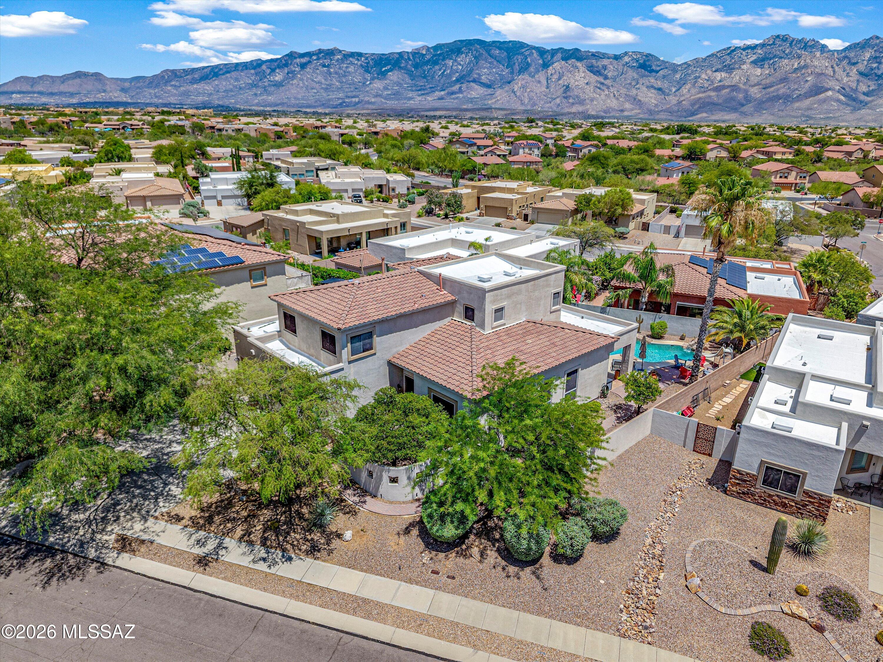Exceptional 5BR/3BA Rancho Vistoso estate presented by Oro Valley's premier luxury brokerage. Soaring ceilings, a dramatic curved staircase, a beautifully renovated chef's kitchen, a custom reclaimed wood fireplace wall, newer flooring throughout and breathtaking Catalina Mountain views combine to create a truly exceptional offering. The spacious 21x16 primary suite features a beautifully updated spa-inspired bath and private view deck, while the backyard delivers a resort-style experience complete with a pool, spa, slide, fire pit and multiple outdoor living spaces.
Beyond the impressive architecture lies a home thoughtfully transformed for today's luxury buyer. The recently renovated chef's kitchen serves as the centerpiece of the home, anchored by an oversized natural stone island with seating, extensive white shaker cabinetry, a farmhouse apron sink, built-in wine refrigerator, built-in microwave and wall oven, gas cooktop with stainless vent hood, marble-inspired backsplash, designer lighting and abundant prep and storage space. The kitchen flows seamlessly into the family room and breakfast nook, creating an ideal setting for everyday living and entertaining.
The family room is anchored by a striking custom fireplace feature wall with built-in display niches and offers a warm, inviting space to gather. Just beyond, the breakfast nook captures beautiful Catalina Mountain views, while the separate formal dining room provides an elegant setting for holidays, dinner parties, and special occasions.
The impressive living room welcomes guests with soaring ceilings, tray ceiling accents, abundant natural light, and a dramatic curved staircase that creates a striking architectural focal point. Combined with the separate family room, formal dining room, and breakfast nook, these thoughtfully designed spaces offer exceptional flexibility for both intimate gatherings and grand-scale entertaining. .
Upstairs, the primary retreat delivers the private escape every homeowner deserves. Step onto your expansive private view deck and take in sweeping Catalina Mountain views before retreating to a beautifully updated spa-inspired bathroom featuring a freestanding soaking tub, spacious walk-in shower with designer tile finishes, frameless glass enclosure, dual vanities, elegant fixtures, and luxury finishes throughout. The thoughtfully designed floorplan also includes four additional bedrooms, highlighted by a desirable main-level guest suite arrangement with a full bathroom nearby, providing exceptional flexibility for guests, multigenerational living, or a private home office. 
The backyard rivals many luxury resorts, offering a sparkling pool and spa with waterfall and slide, expansive covered patio, fire pit gathering area, mature landscaping, and multiple spaces to relax, entertain, and enjoy Arizona's spectacular sunsets. Whether hosting family and friends or enjoying a quiet evening under the stars, this outdoor environment was designed to be experienced.
Located within the highly sought-after Rancho Vistoso community, residents enjoy convenient access to parks, walking and biking trails, golf, shopping, dining, and Amphitheater District schools. Combining exceptional upgrades, mountain views, resort-style amenities, and one of Oro Valley's most desirable locations, this is a rare opportunity to own a truly move-in-ready luxury home.