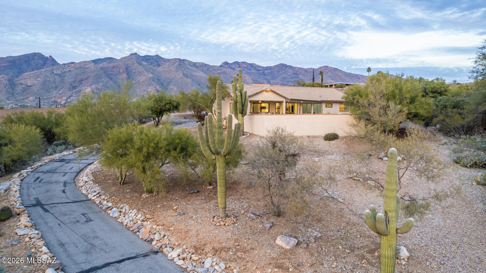 Perched in the Catalina Foothills, this beautifully remodeled home offers open living, sweeping city and mountain views, and a quiet setting. Updated Windows and insulation throughout to keep out all the road sound!! Thoughtfully updated with quality finishes throughout, the home lives far larger than its footprint, enhanced by an open floor plan, soaring ceilings, and expansive walls of glass that frame Tucson's city lights and surrounding mountain ranges. The main living area feels bright and open, with natural light coming in through south- and west-facing windows. The expansive windows capture sunsets and city views while the interior remains calm and peaceful. Every room in the home connects to the outdoors, with city and mountain views from each space. The kitchen features quartz countertops, a generous island, stainless steel appliance and modern finishes. It opens directly to the main living areas, making it ideal for both entertaining and everyday living, with clear sightlines to the views beyond. The primary suite offers a comfortable retreat, complete with a walk-in closet and spa-inspired bathroom featuring a soaking tub, oversized shower, and dual vanities creating a relaxing, private space. Additional highlights include large attached storage units, a two-car garage with epoxy-coated floors, fireplace, and extensive remodeling throughout that gives the home a move-in-ready feel. This home sits just minutes from the Catalina Mountains, Ventana Canyon Trailhead, and Sabino Canyon Recreation Area, offering easy access to hiking, biking, and outdoor activities. La Encantada provides nearby upscale shopping and dining, and the property is conveniently positioned near golf courses, resorts, and District 16 schools, while still maintaining a tucked-away Foothills setting.