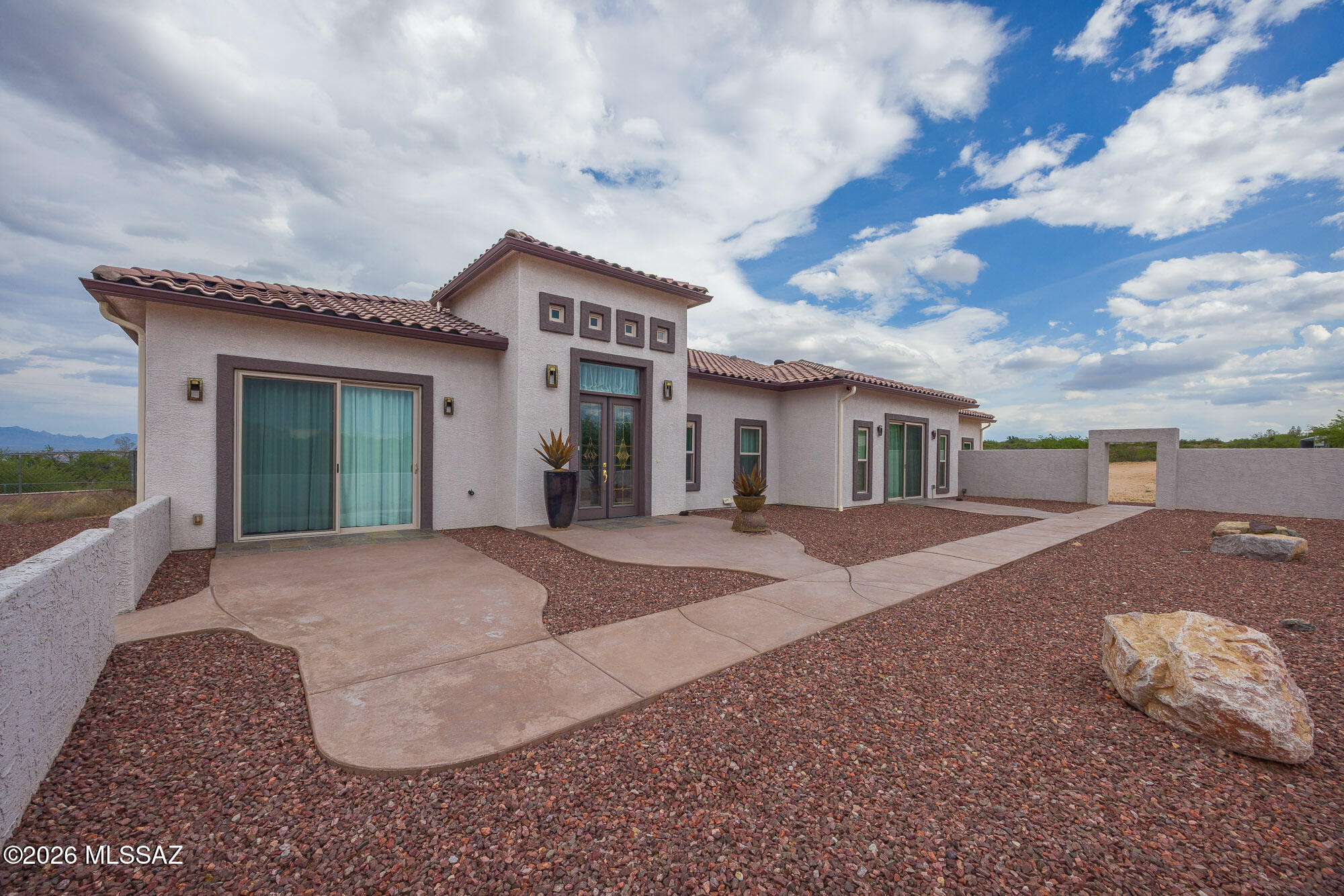 Experience luxury desert living on this expansive 4.01-acre estate. This meticulously designed 4-bedroom, 4-bathroom home features two primary suites with private en-suites: one is fully handicap accessible with a convenient wet bar, while the second offers a cozy fireplace retreat. Every bedroom is flooded with natural light through large sliding glass doors that seamlessly blend indoor and outdoor living. The heart of the home is a true chef's kitchen, boasting elegant granite countertops, high-end LVT flooring, and a functional layout perfect for entertaining. Step outside to a private oasis featuring a relaxing spa, a tranquil fountain, and two dedicated dog runs, all set against the breathtaking backdrop of the Benson landscape.