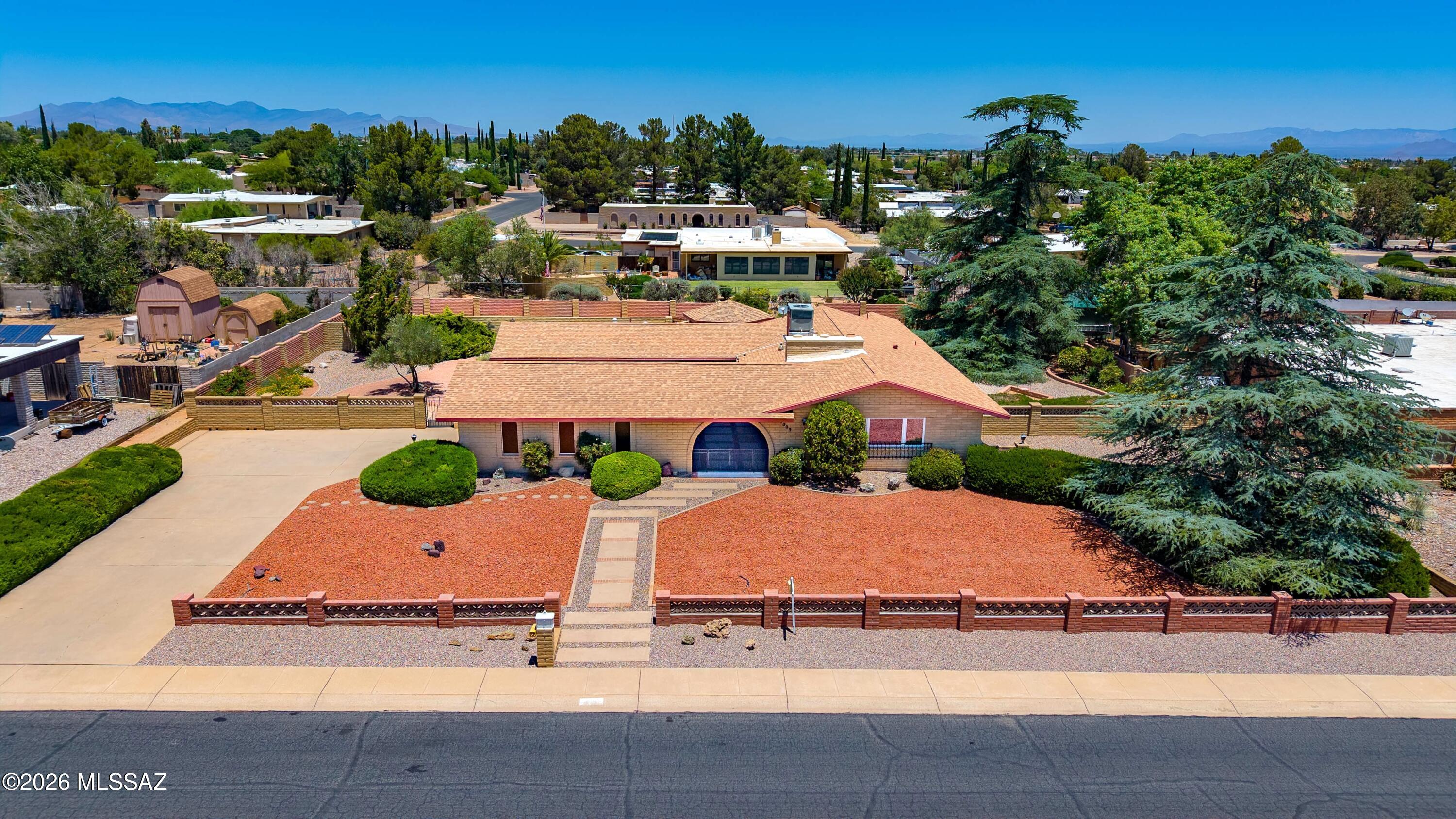 This custom-built 1976 Blankenship slump block home blends timeless craftsmanship with warm character and inviting outdoor living. Offering 2,017 sq ft, 3 bedrooms and 2.5 bathrooms, this well-maintained property showcases pride of ownership from the beautifully manicured front and back landscaping to the thoughtfully designed interior details throughout. The inviting space between the home and 2 car garage features custom touches, a built-in fold-out standing bar, and seating - perfect for entertaining. The breezeway leads to the backyard retreat. Step through the double solid wood doors into a welcoming foyer featuring unique see-through built-in shelving and parquet wood floors. The living area is anchored by a stunning custom rock fireplace and an elegant archway leading into the cozy family room.
The dining room features a built-in see-through hutch that adds charm and functionality. In the kitchen you will find abundant storage, laminate countertops, breakfast bar seating, a newer Bosch dishwasher, electric range, and refrigerator that conveys. The newer washer and dryer (2022) will convey as well. The family room is complete with custom, built-in wood shelving, desk space ideal for crafting or a home office, and peaceful backyard views.  The spacious primary suite features luxury vinyl plank flooring, a walk-in closet, and a beautiful custom wood bed surround with built-in storage.
Anderson windows and doors throughout the home enhance both beauty and efficiency, including 2 gorgeous Anderson sliding doors - one opening to the relaxing breezeway from the bedroom wing hallway, and the other one in the family room opening to the backyard.
Outside, enjoy peaceful landscaping with an irrigation system, multiple rain catchment barrels, a block gazebo, and a built-in barbecue area with storage--perfect for entertaining or relaxing Arizona evenings. A separate yard area with alley access offers excellent space for gardening, pets, recreational toys, or additional flexibility. This home includes countless custom details, making it a one-of-a-kind Sierra Vista home.