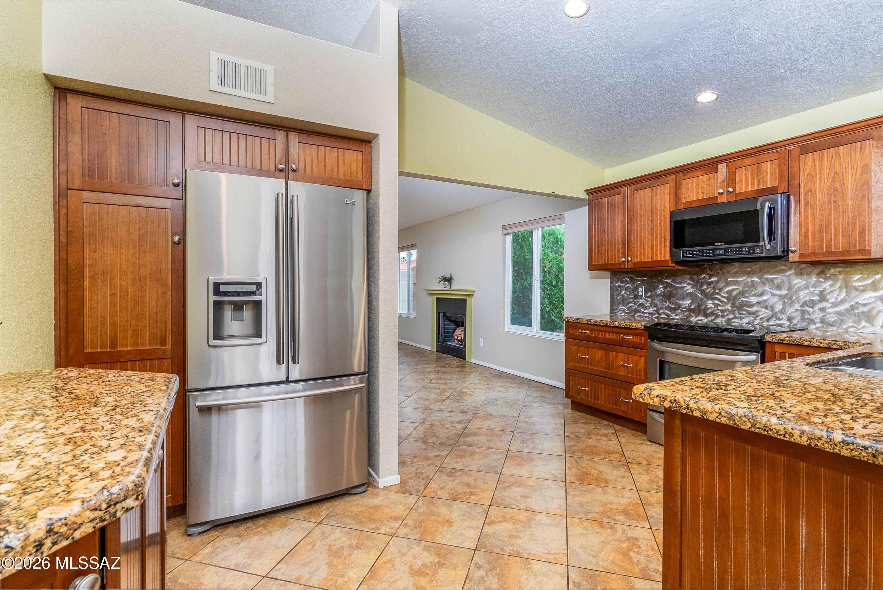 Welcome home to this bright and inviting single-story residence, perfectly situated on a premium corner lot that is one of the largest in the neighborhood! Offering 2 bedrooms, 2 bathrooms, and a versatile den/flex space in 1,299 square feet, this home combines comfort, functionality, and thoughtful updates throughout.  The spacious living room features a cozy wood-burning fireplace, built-in shelving, and plenty of natural light. The tiled flex room with sliding doors provides endless possibilities as a home office, gym, hobby room, or could easily be converted into a third bedroom.  The updated kitchen is designed for both everyday living and entertaining, showcasing beautiful wood cabinetry with crown molding, granite countertops, stainless steel appliances, and ample storage.  Step outside to an entertainer's backyard complete with a built-in BBQ, built-in smoker, raised garden beds, an electric retractable awning for added shade, a storage shed, and direct gate access to the wash for additional privacy and outdoor enjoyment.  Major improvements provide peace of mind, including a brand-new 3-ton HVAC system with a 10-year warranty, new thermostat, newer water softener, newer exterior paint, a recently recoated flat roof section, and no polybutylene plumbing. Tile flooring runs throughout the home except in the bedrooms, and the guest room includes a convenient Murphy bed. All appliances convey, including the refrigerator, washer, and dryer.  Located directly across from the community pool, you'll enjoy easy access to a refreshing escape on warm Arizona days. Conveniently situated just minutes from shopping, restaurants, medical facilities, schools, hiking trails, and Interstate access, this move-in-ready home offers the perfect blend of location, lifestyle, and value.  Don't miss your opportunity to make this exceptional home yours!