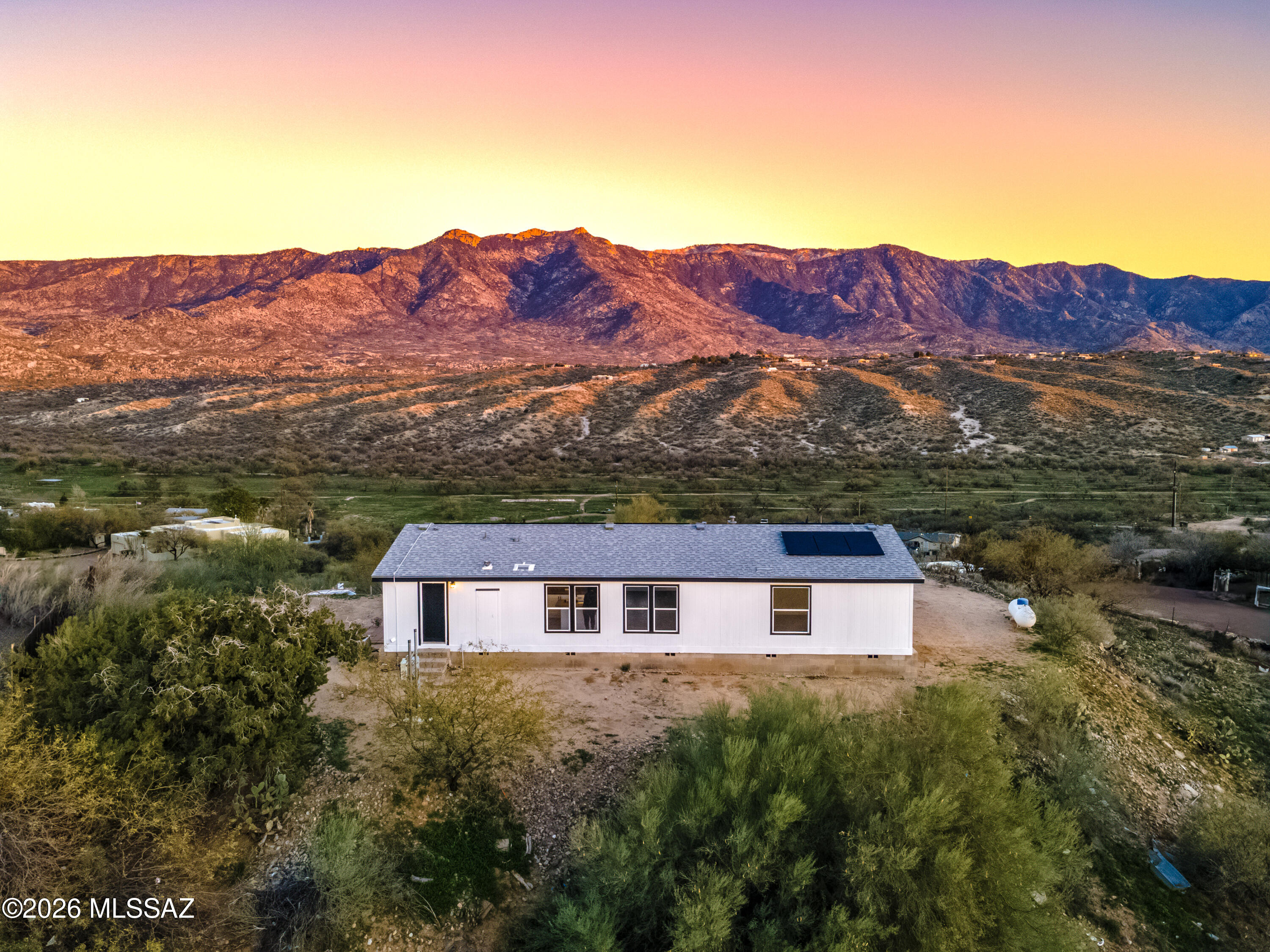 MOTIVATED SELLER! Discover space, comfort, and scenic views on this beautifully updated 1-acre property. This 3-bedroom, 2-bath manufactured home offers 1,568 square feet of well-designed living space and features fresh interior and exterior paint throughout. The open-concept floor plan showcases vaulted ceilings, wood-look flooring, and a neutral color palette that complements any style. The kitchen includes white cabinetry, a pantry, and a center island with breakfast bar seating—ideal for everyday living and entertaining. The spacious primary suite features plush carpet, a walk-in closet, and a private en-suite bath. Solar power enhances energy efficiency and offers long-term savings. Enjoy peaceful mountain views and the freedom of wide-open space. Owner/Agent