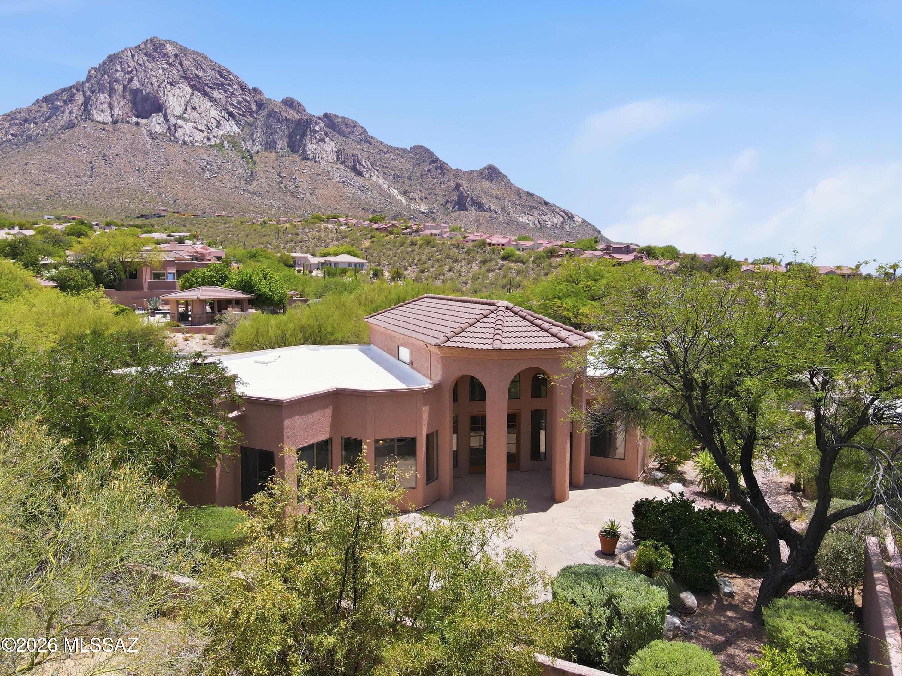 Perched high on the rugged slopes of the Catalina Mountains, this sophisticated 3BD/2.5BA (2,177sqft) residence offers a rare blend of elevated privacy and dramatic desert backdrops. Located within La Reserve, Oro Valley's premier guard-gated mountainside community, this single-story home perfectly captures the essence of refined Southwestern living. Pass through the grand foyer entry to discover an open-concept contemporary layout illuminated by high ceilings and generous window placements. Designed for both effortless relaxation and upscale entertaining, the home flows into an elegant great room anchored by a custom fireplace, creating a warm and inviting focal point. The adjacent kitchen is a chef's delight, maximizing efficiency with a large convenient breakfast bar, and an abundance of clean cabinetry and counter storage. Ceramic tile flooring stretches across the main living areas, complementing the neutral, light-filled aesthetic. The thoughtfully private split-bedroom layout ensures maximum comfort for both owners and guests. The primary suite serves as a true resort-style sanctuary, offering a spacious walk-in closet, a dedicated door leading straight out to the rear patio, and a luxurious spa like bathroom, complete with a deep garden tub and a separate walk-in shower. Step outside to experience a meticulously manicured, low-care backyard oasis enclosed by natural desert landscaping. Whether relaxing beneath the deep covered patio or dining al fresco under the stars, the elevated vantage point delivers breathtaking views of the mountain silhouettes. Beyond your front door, enjoy exclusive neighborhood amenities including a pristine community pool and spa, all while being minutes away from premier shopping at Oracle Road, top-rated schools, and local hiking trails.